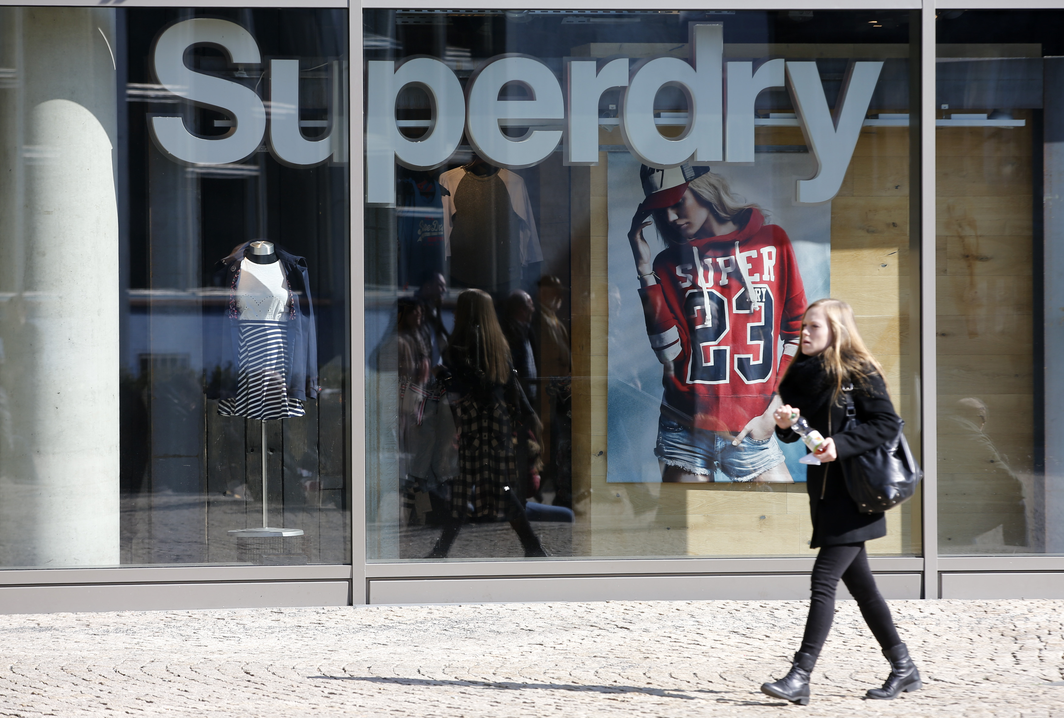 A woman walks past a Superdry fashion store in Berlin