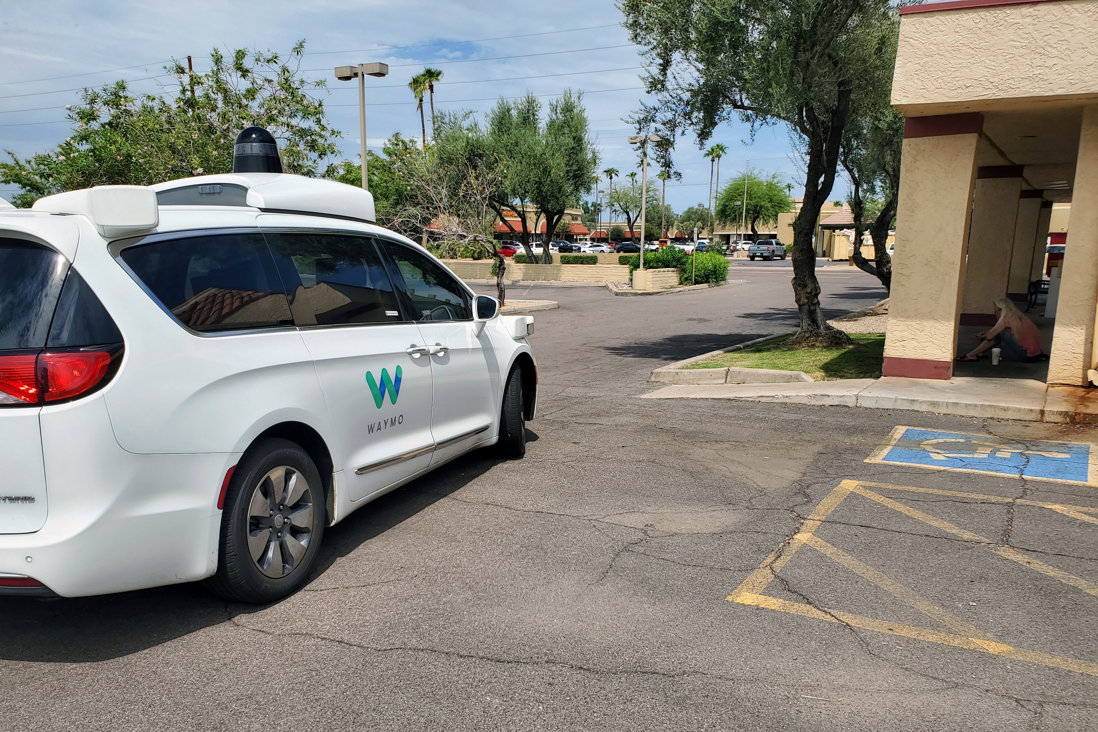 Driverless Waymo Chrysler Pacifica minivan partially blocks access to a disabled parking space in Tempe