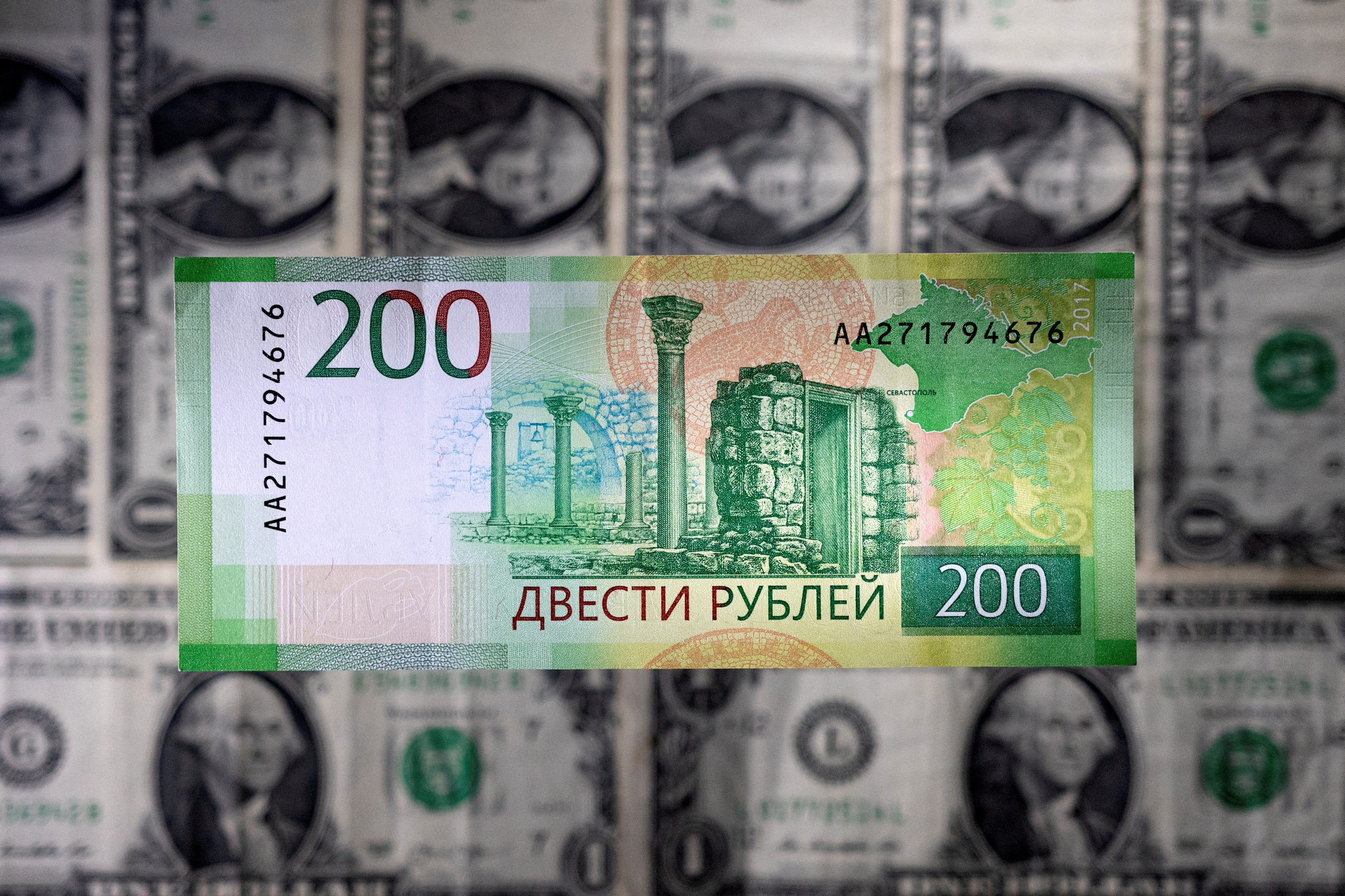 Illustration shows a Russian rouble banknote placed on U.S. dollar banknotes