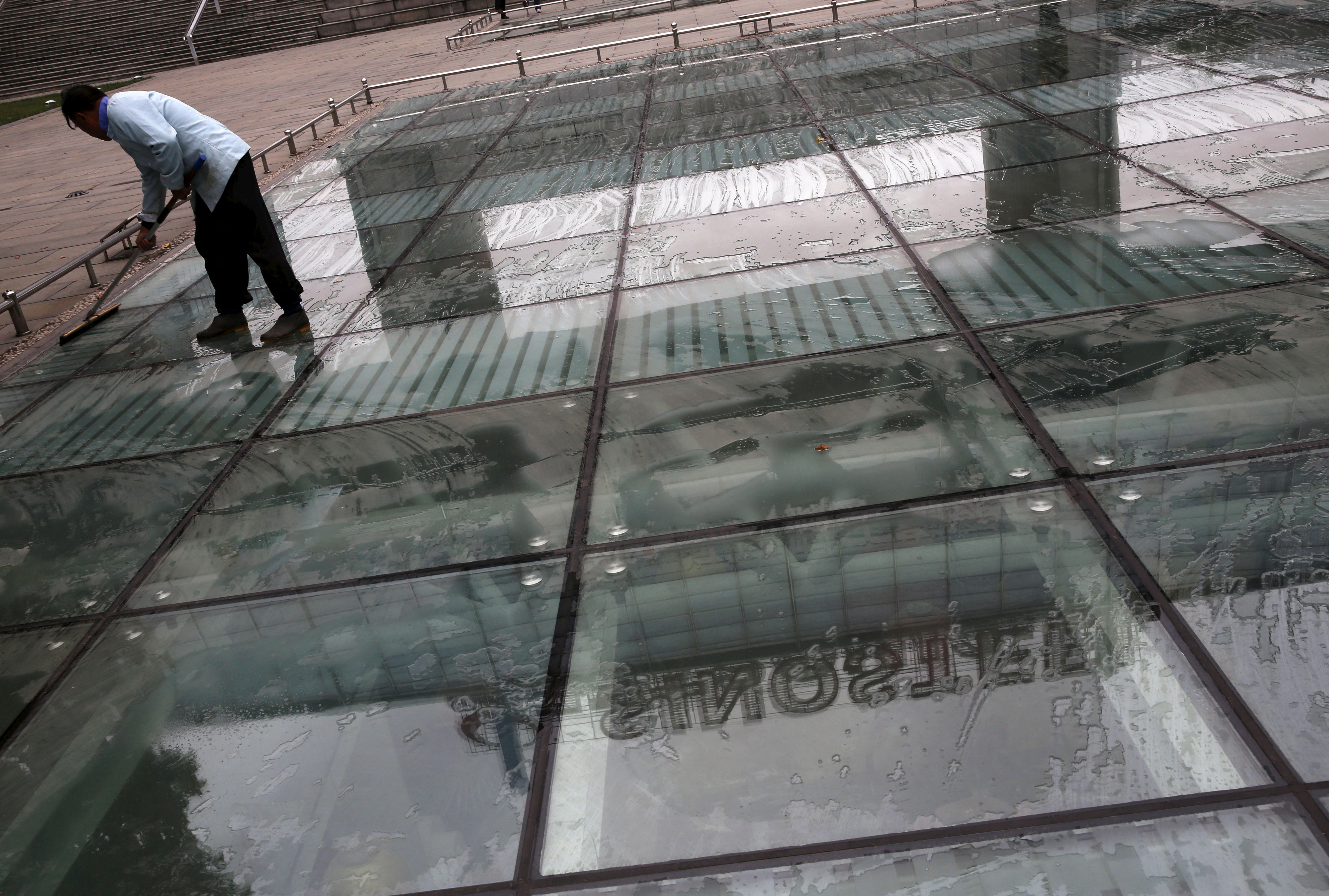 A worker cleans a glass floor reflecting Sinosteel's logo, in front of itsheadquarters building in Beijing