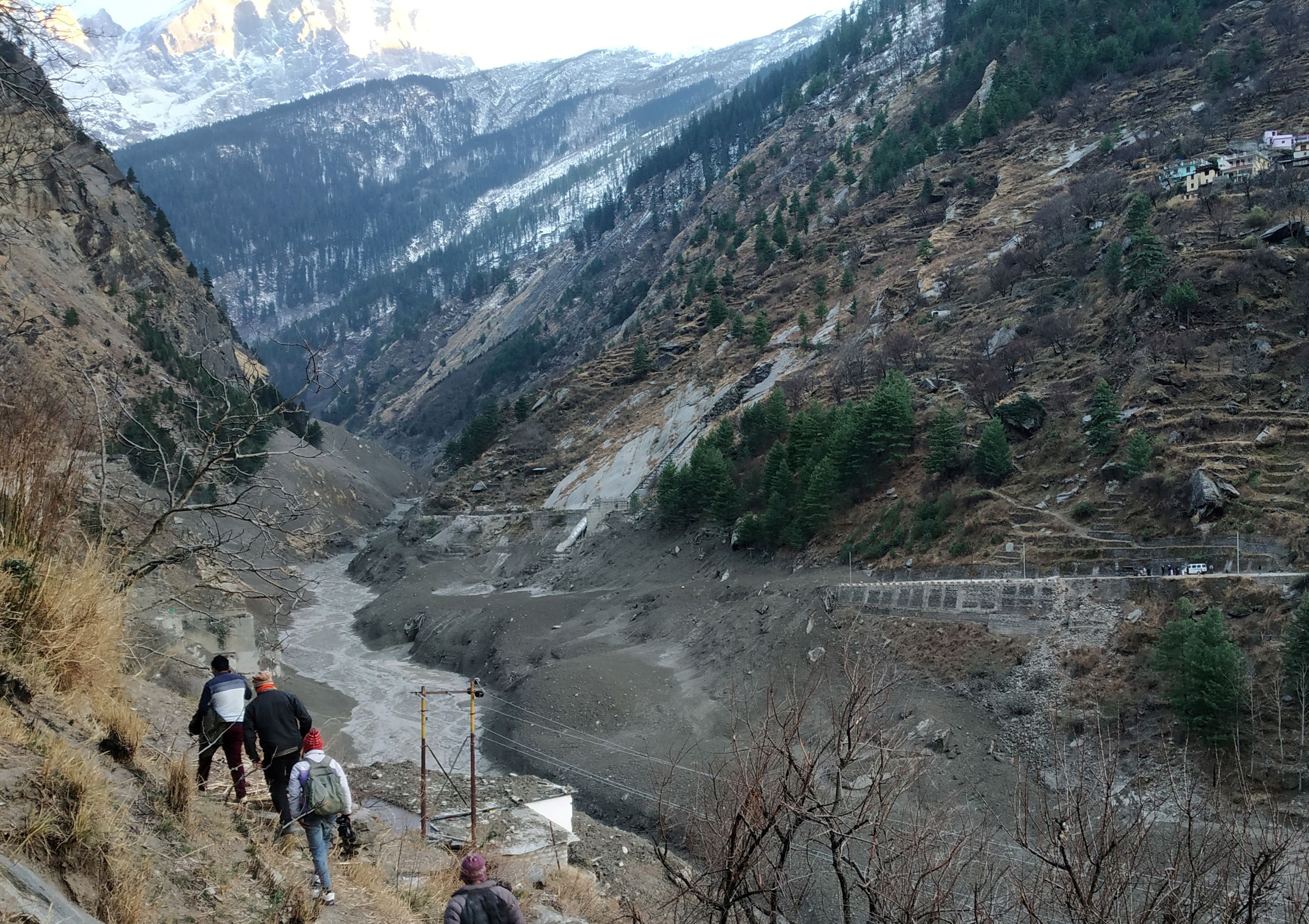 People walk past a destroyed dam after a Himalayan glacier broke and crashed into the dam at Raini Chak Lata