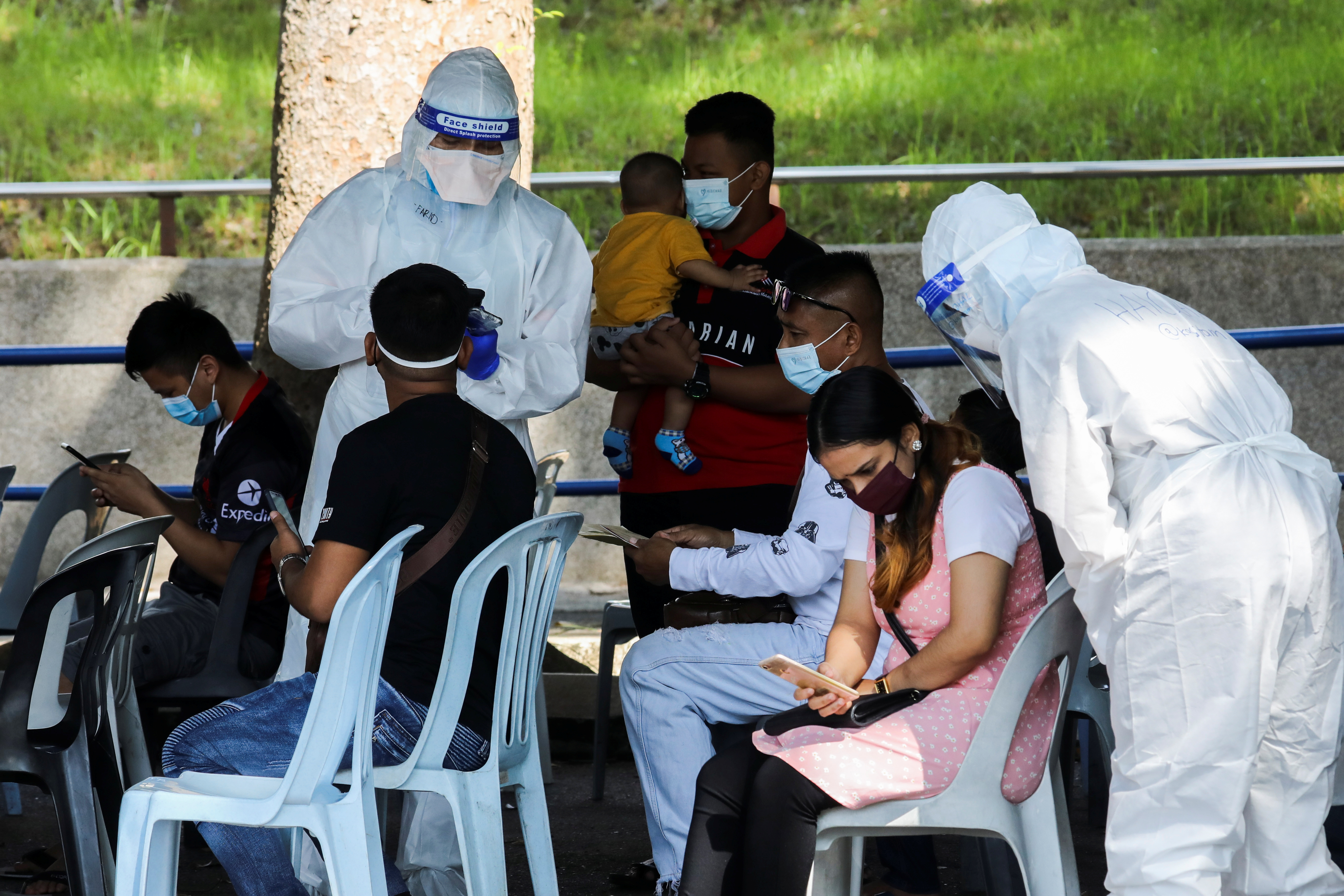Medical workers speak to people outside a coronavirus disease (COVID-19) assessment centre, in Shah Alam