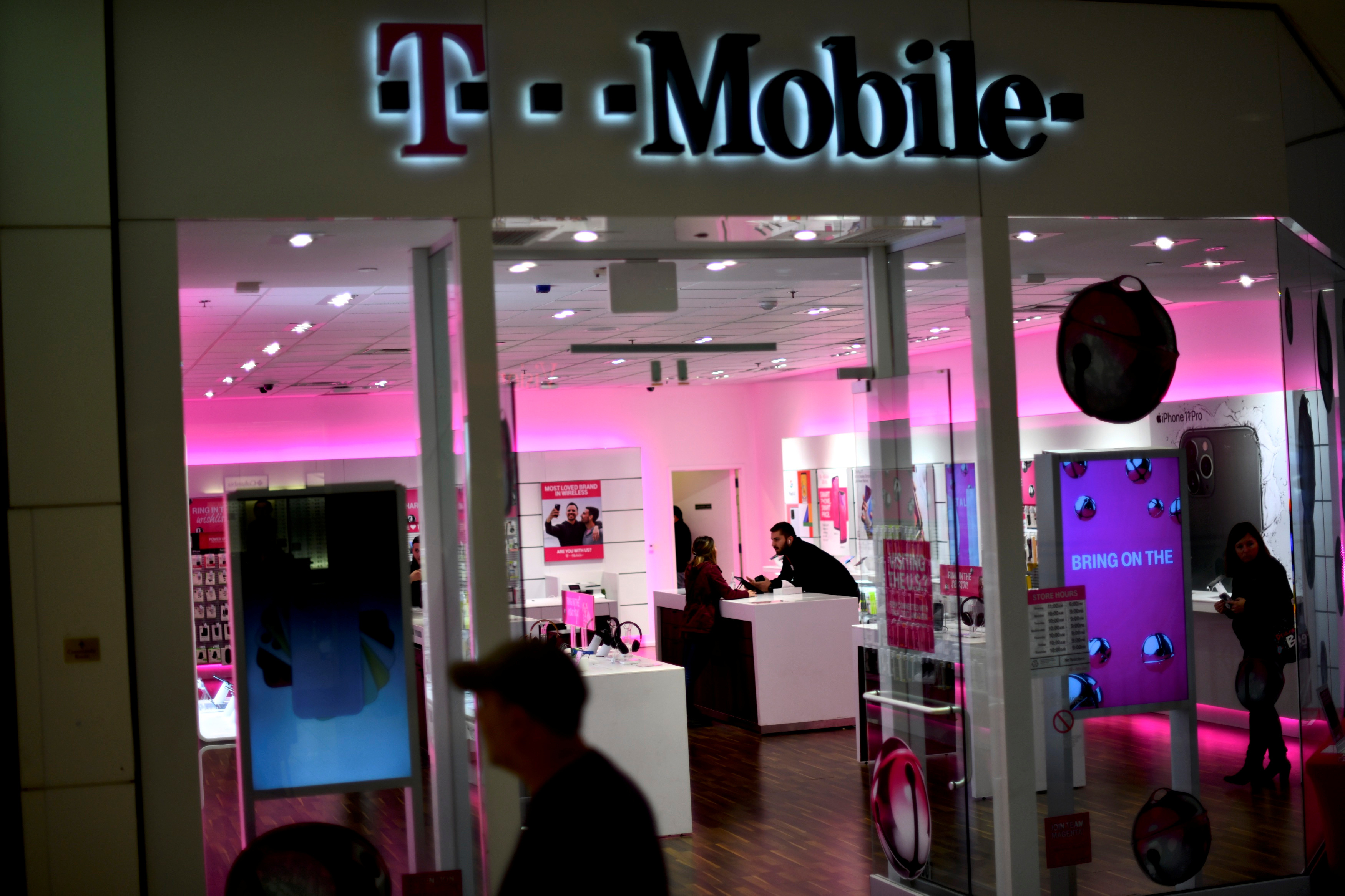 A T-Mobile employee assists a customer as holiday shopping accelerates at the King of Prussia Mall