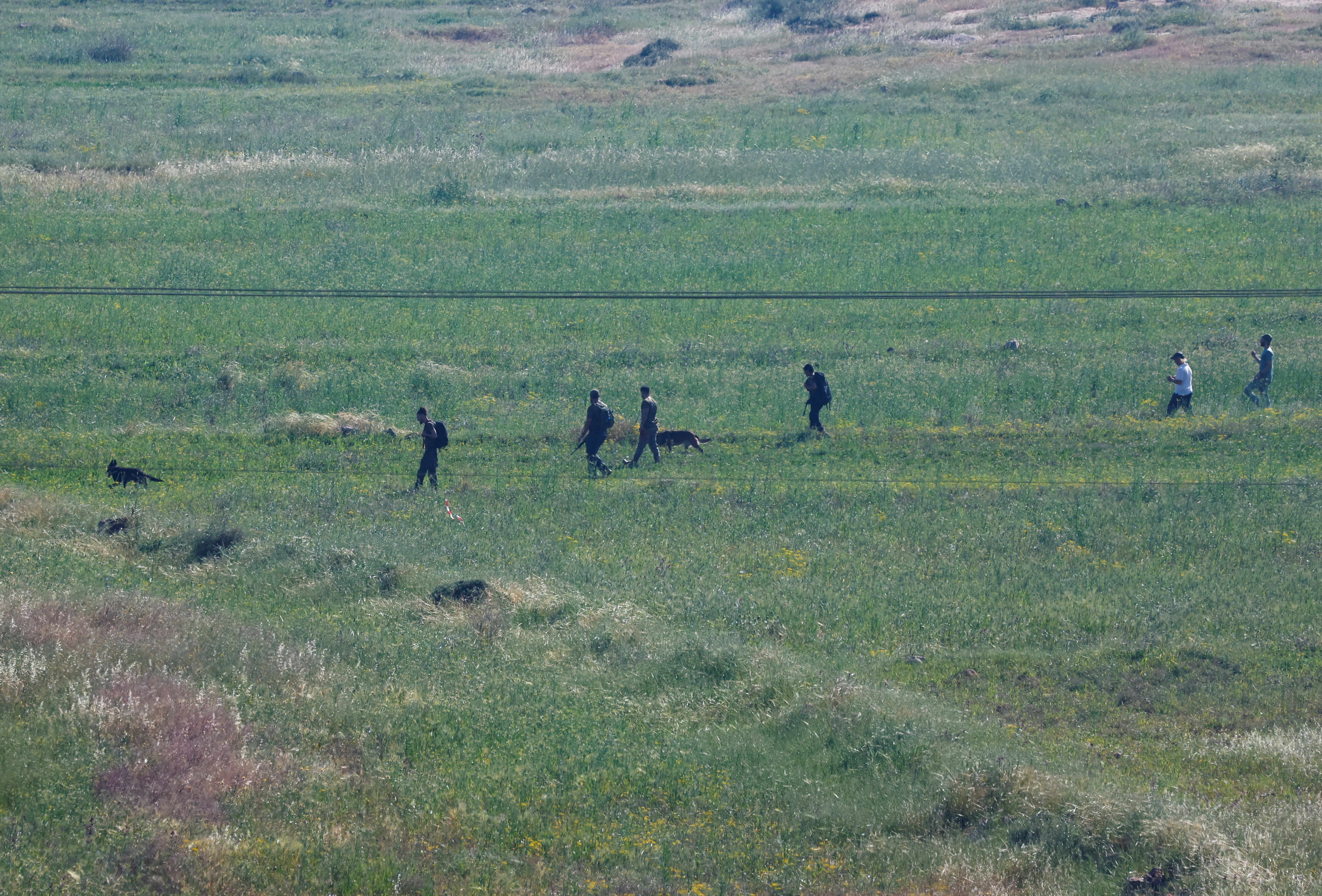 Israeli settlers look for a 14-year-old, who according to the Israeli military went missing in the area near the village of al-Mughayyer