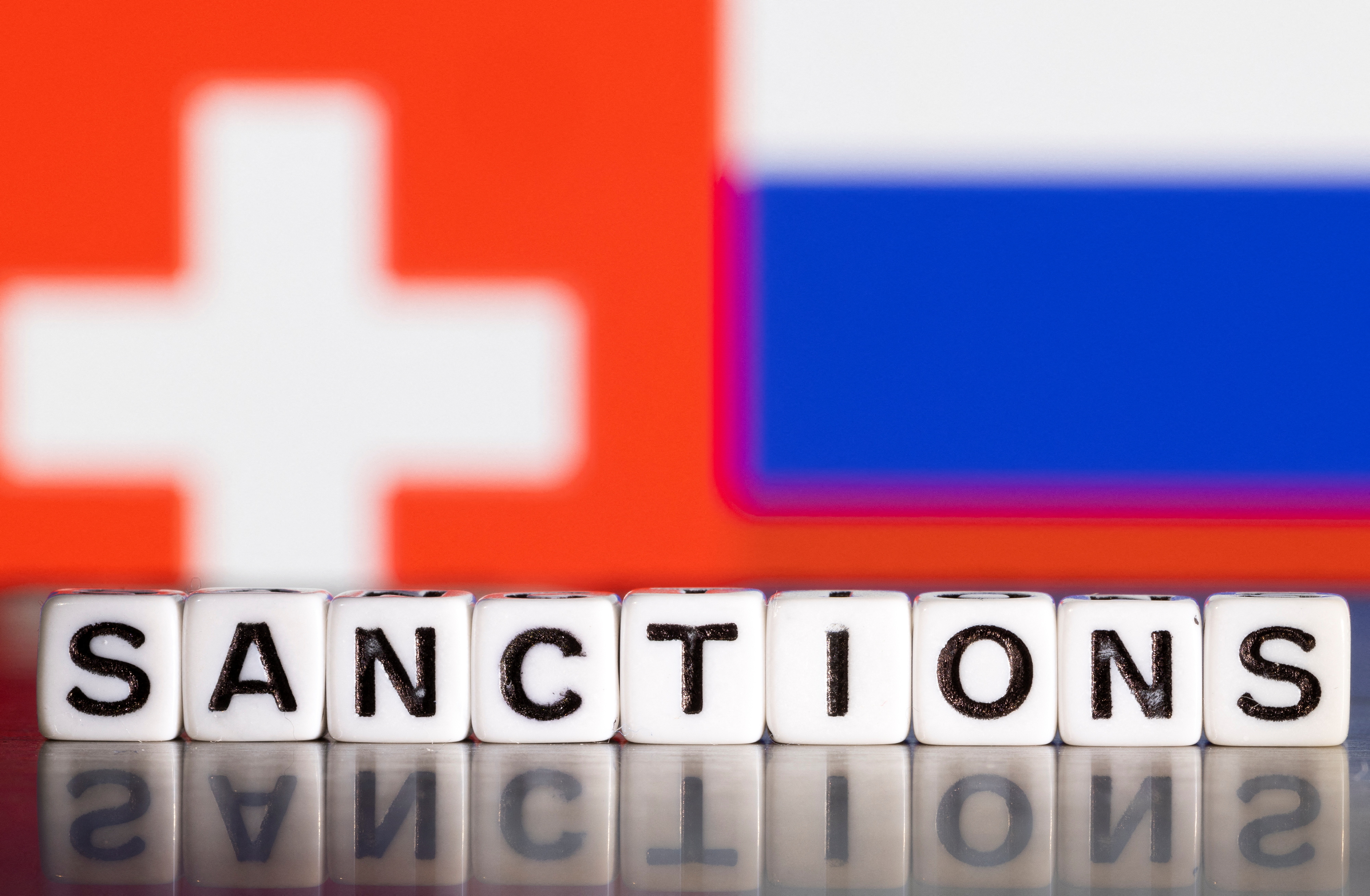Illustration shows letters arranged to read "Sanctions" in front of flag colors of Switzerland and Russia
