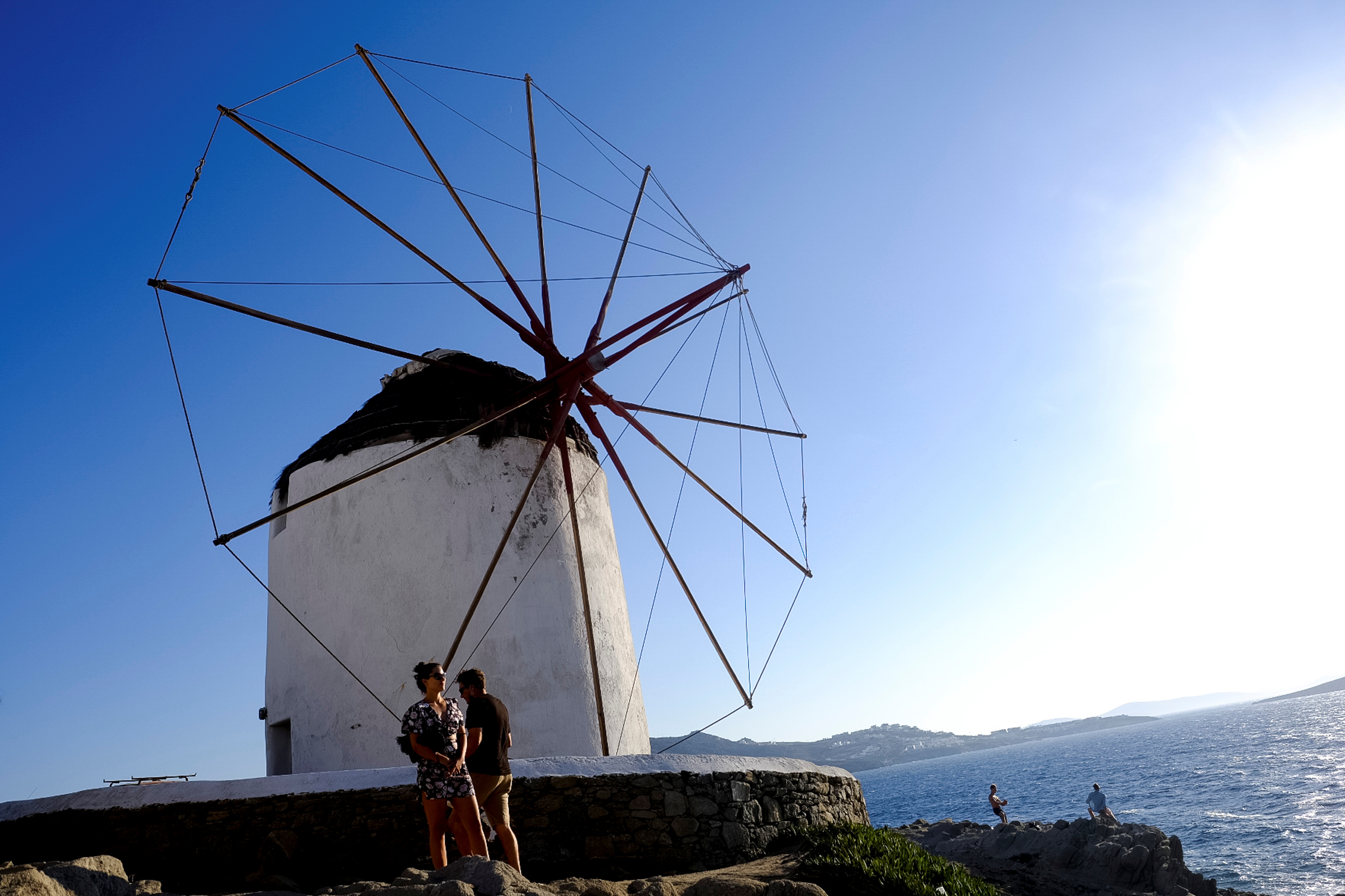 People stand under a windmill on the island of Mykonos