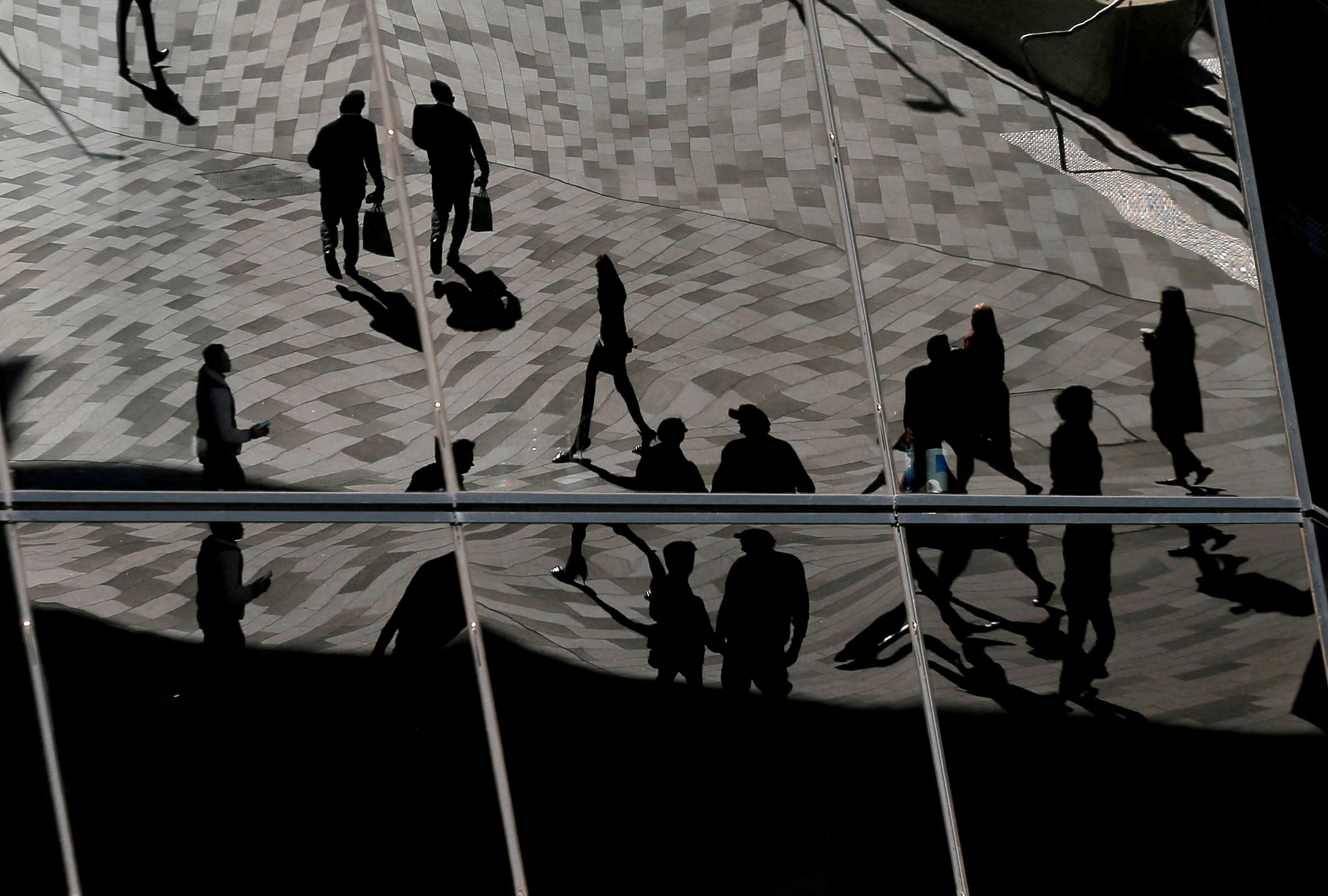 Workers are reflected in the windows of an office building in the Barangaroo business district of Sydney, Australia's largest city.