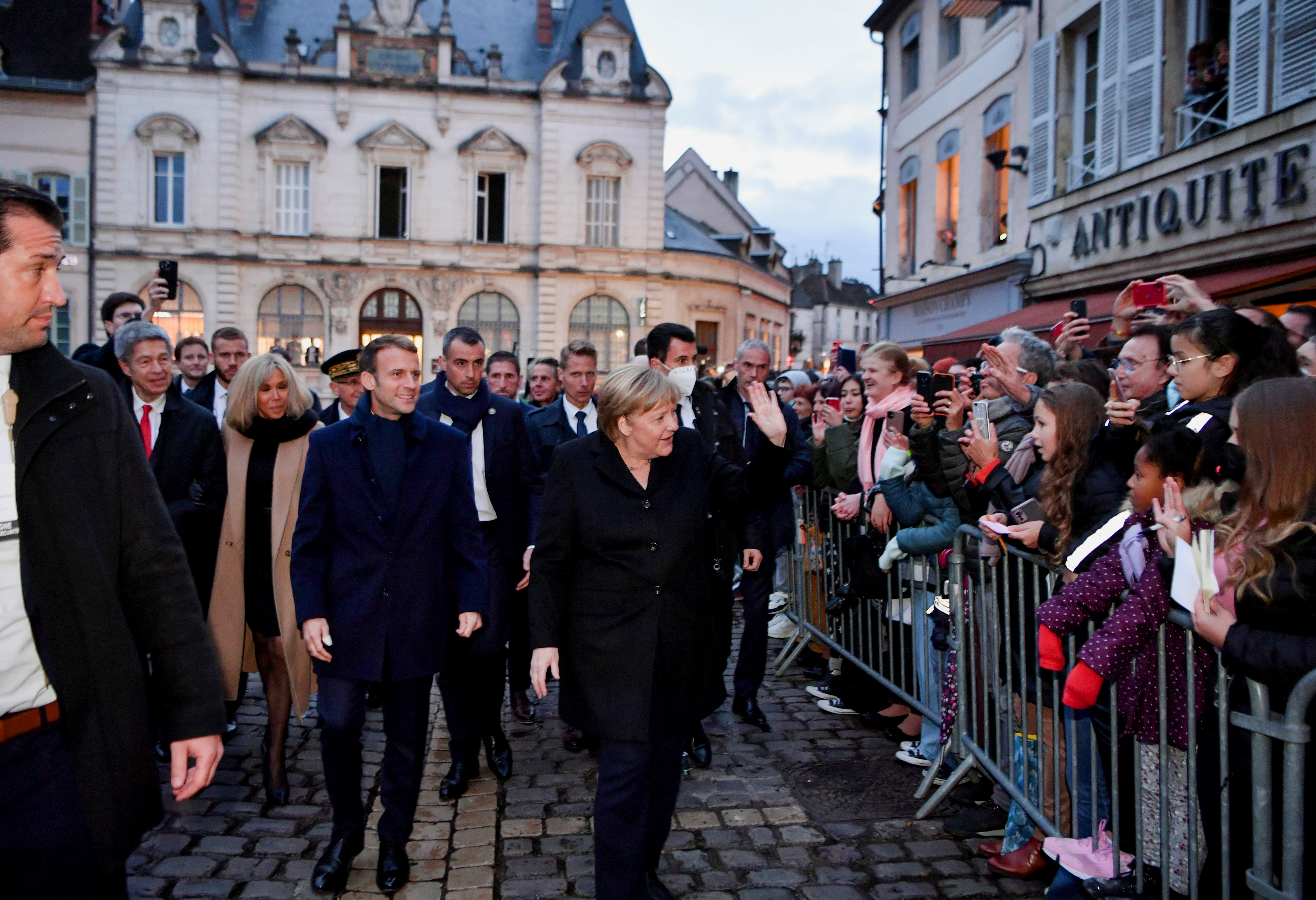 France's President Emmanuel Macron, flanked by his wife Brigitt Macron, is greeted by members of the public with outgoing German Chancellor Angela Merkel upon their arrival prior to talks, in Beaune, France, November 3, 2021. Philippe Desmazes/Pool via REUTERS