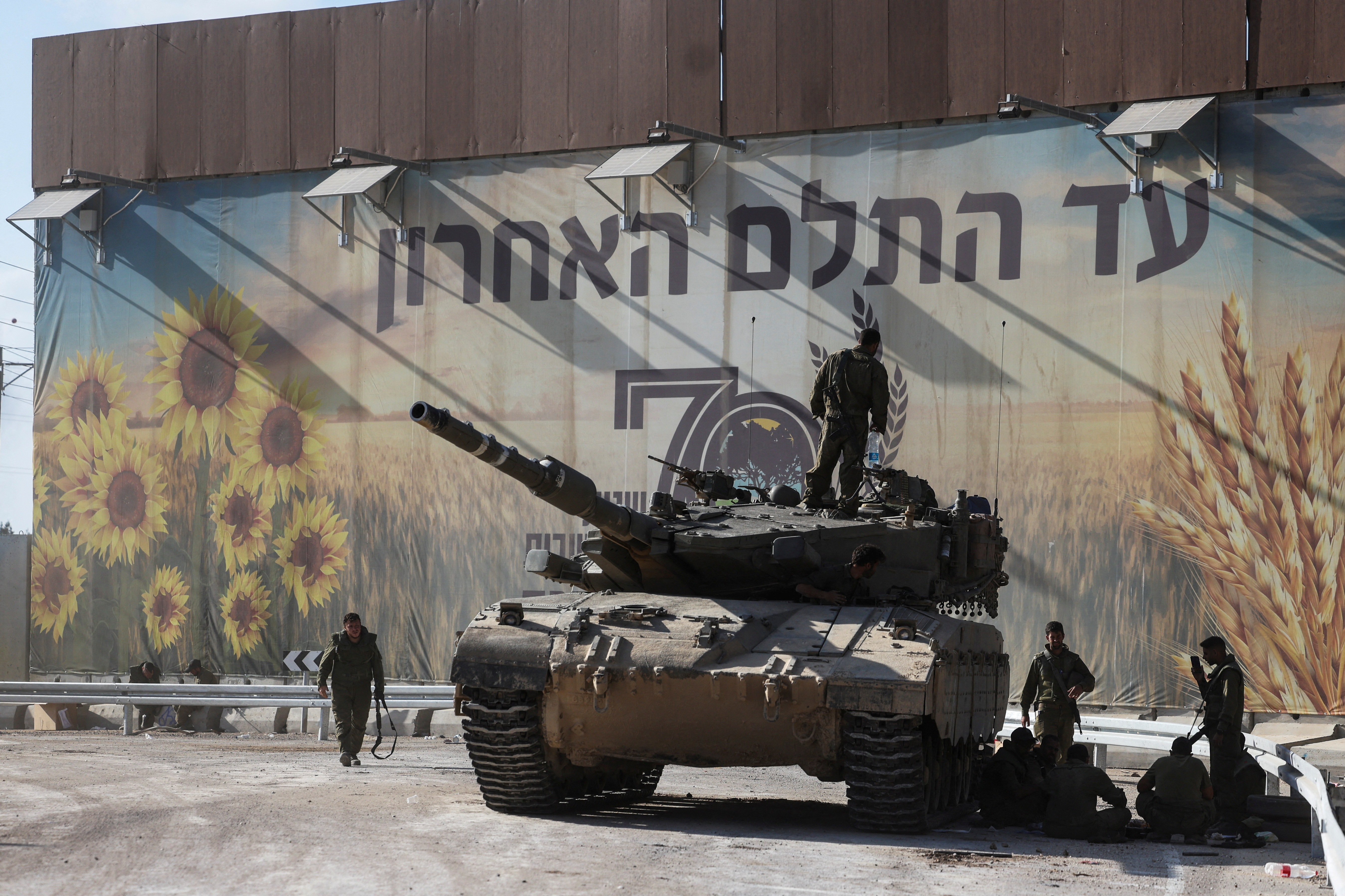 Israeli soldiers gather on and around a tank near Israel's border with the Gaza Strip, in southern Israel
