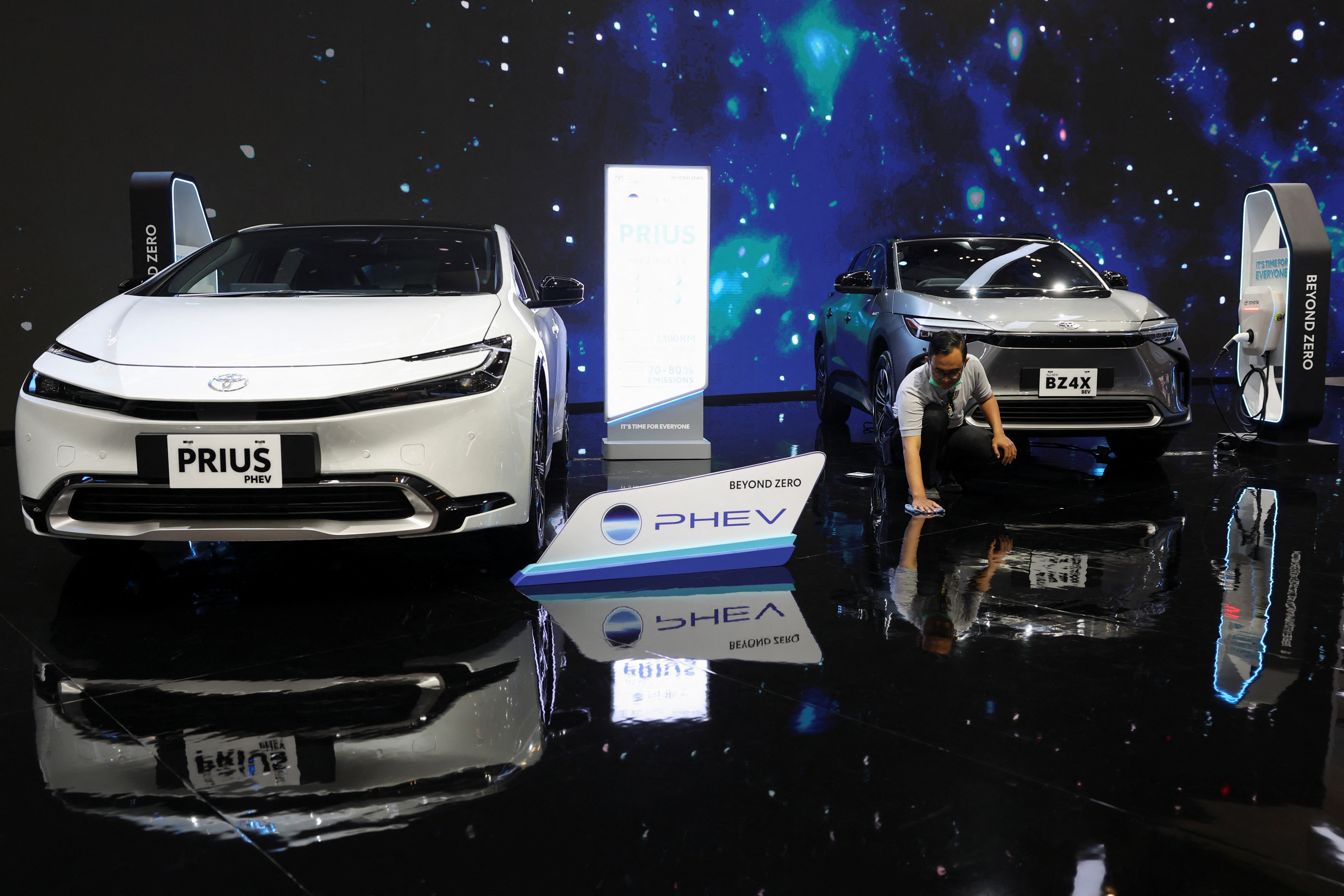 A man wipes the floor near the Toyota Prius PHEV and Toyota BZ4X during the Indonesia International Auto Show in Tangerang