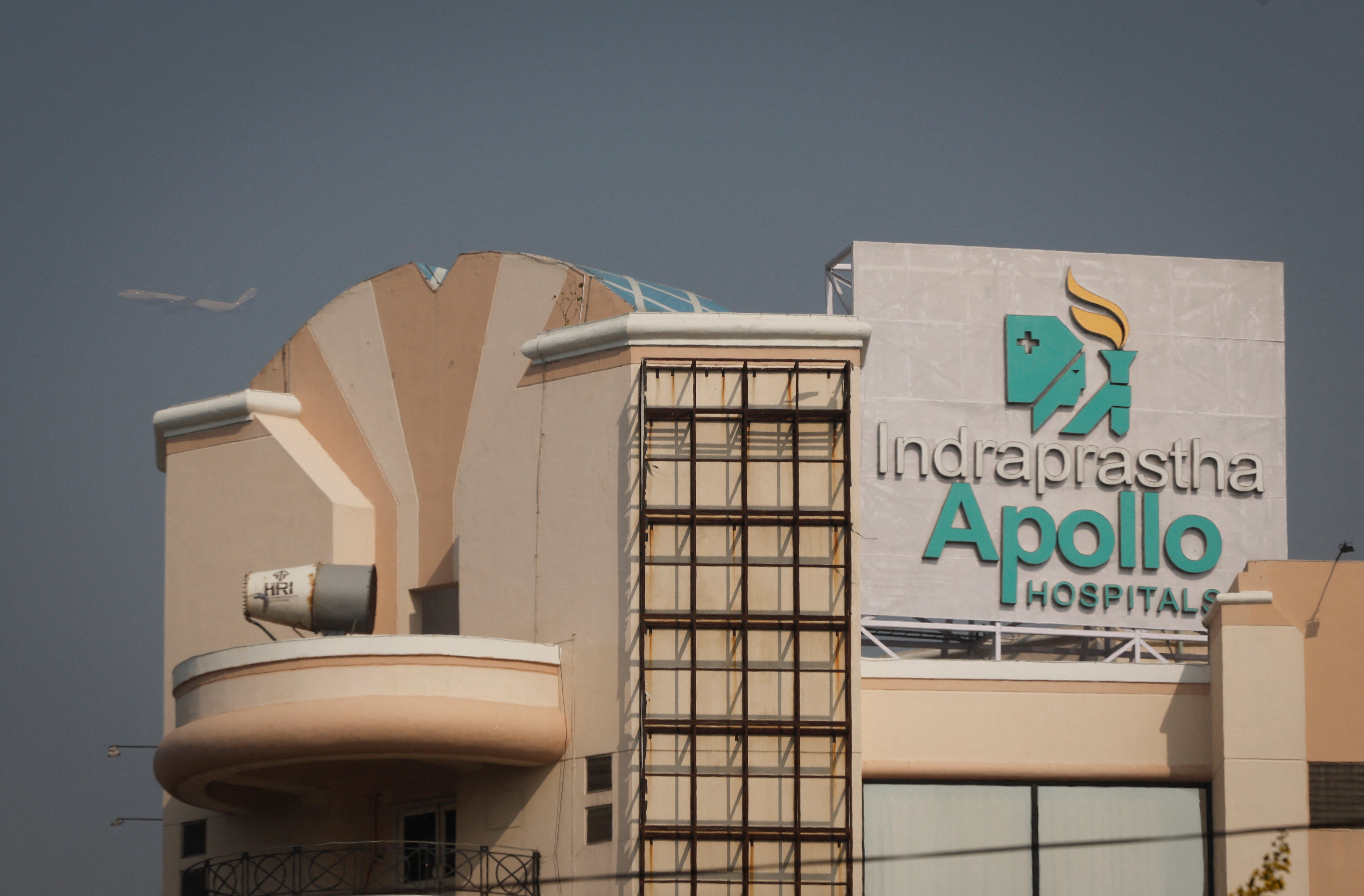 An airplane flies past an Apollo Hospital building in New Delhi