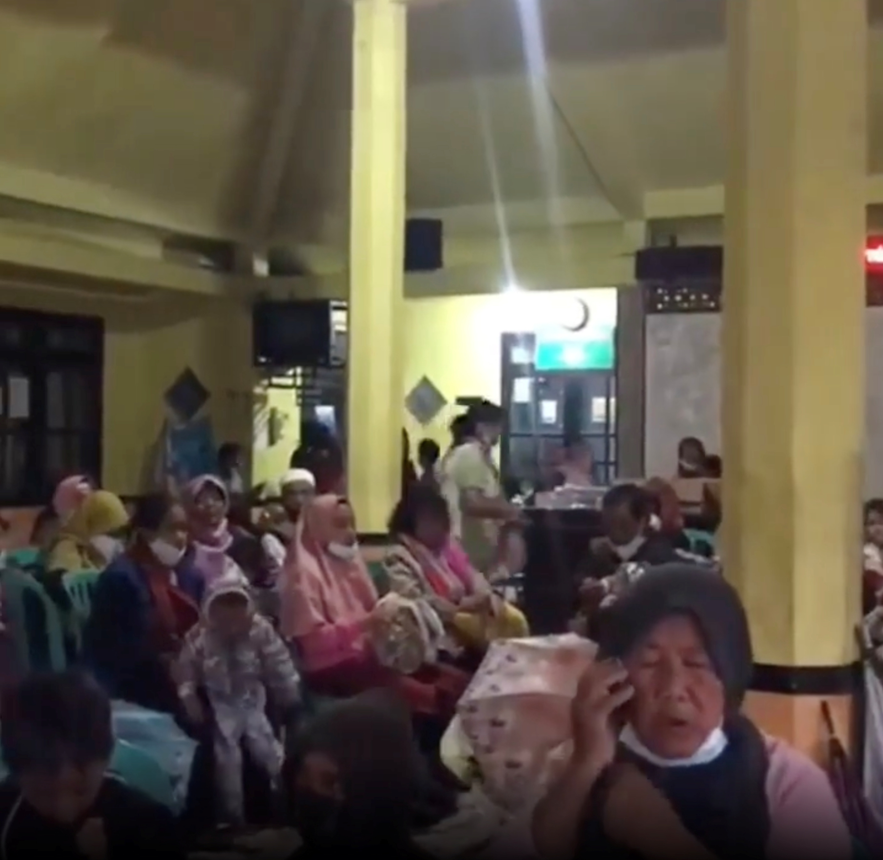 People wait at an evacuation center in Candipuro following the eruption of Indonesia's Semeru volcano, Lumajang, East Java Province, Indonesia December 4, 2021 in this screen grab obtained from a social media video. INSTAGRAM @act_pasuruan/via REUTERS  