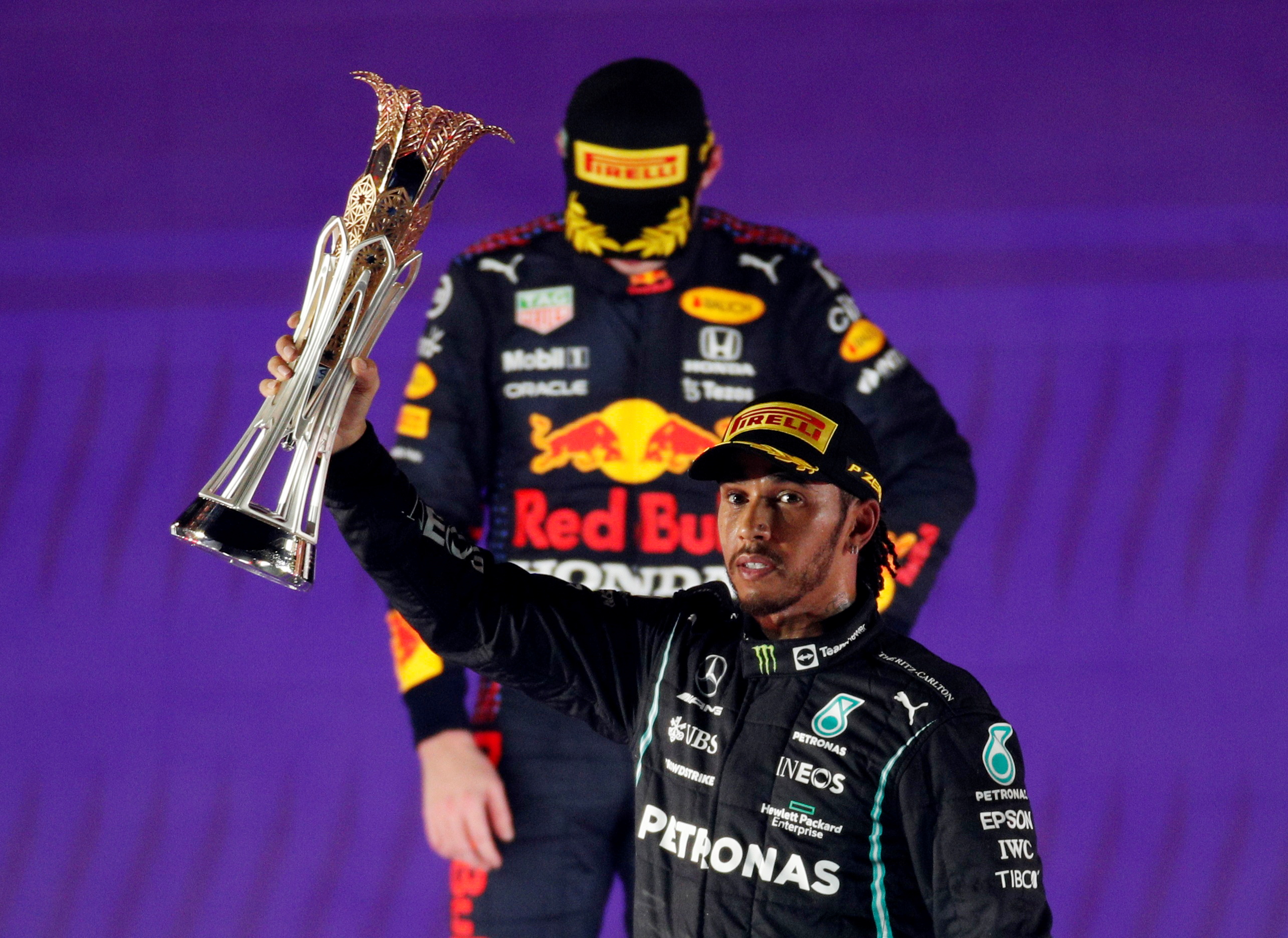 Formula One F1- Saudi Arabian Grand Prix - Jeddah Corniche Circuit, Jeddah, Saudi Arabia - December 5, 2021 Mercedes' Lewis Hamilton celebrates with the trophy on the podium after winning the race as second placed Red Bull's Max Verstappen looks dejected REUTERS/Hamad I Mohammed    