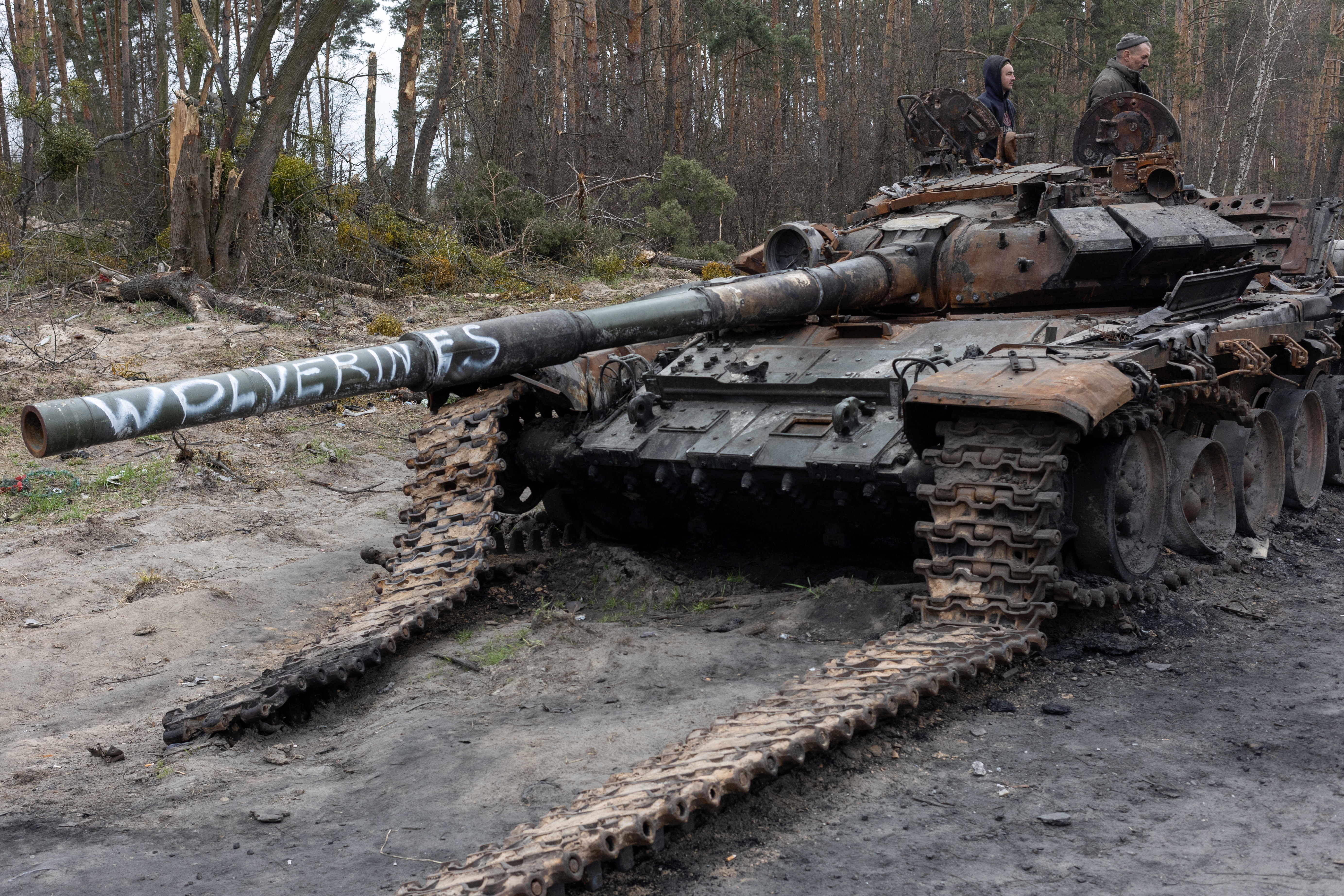 Carroñeros buscan piezas metálicas útiles en un tanque ruso destruido en las afueras de Kiev
