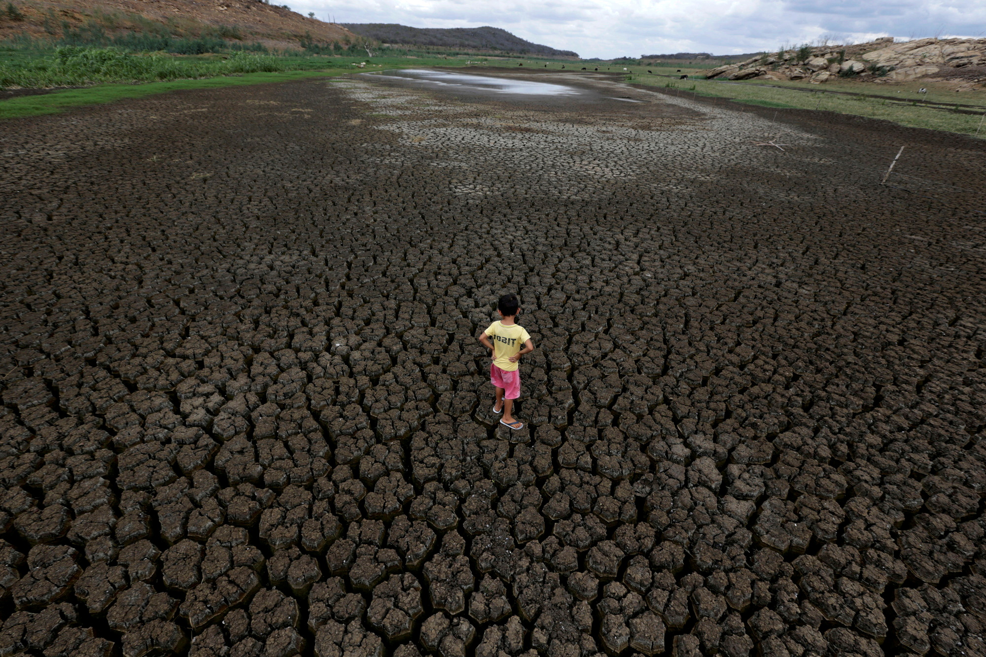 A boy stands on the cracked ground of the Boqueirao reservoir in Brazil
