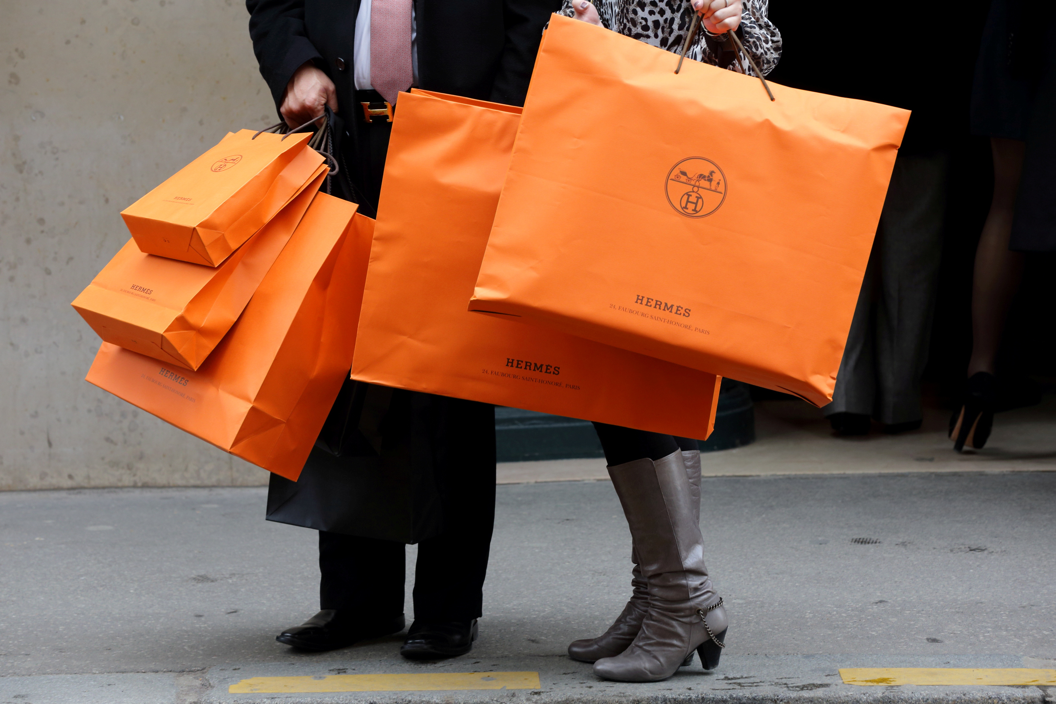 A couple walk with Hermes shopping bags as they leave a Hermes store in Paris, France, March 21, 2013. REUTERS/Philippe Wojazer/File Photo