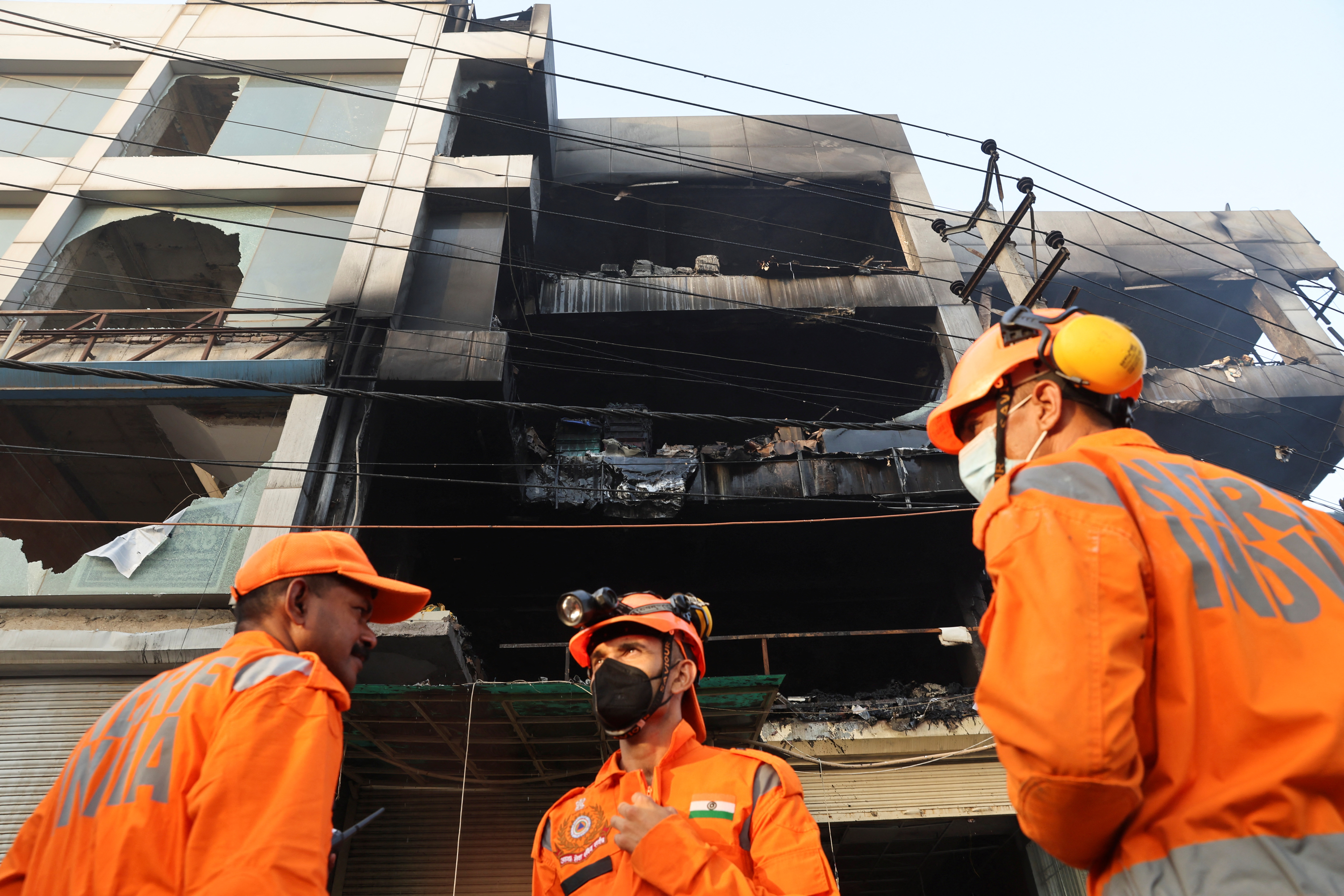 National Disaster Response Force (NDRF) and fire brigade personnel conduct a search and rescue operation after a fire broke out in a commercial building, in New Delhi