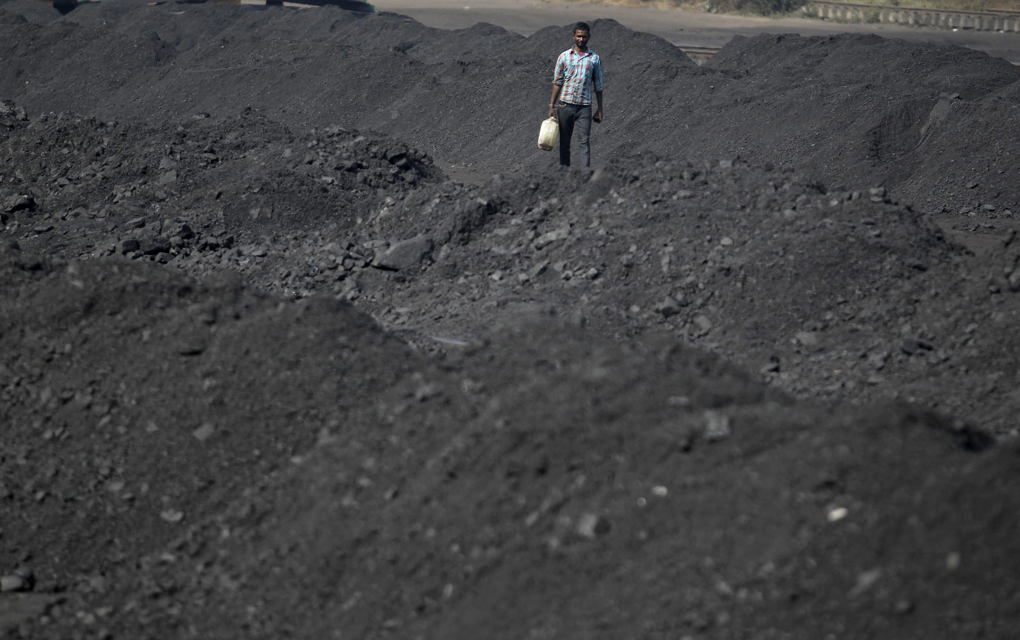 A worker carries a container filled with drinking water at a railway coal yard on the outskirts of Ahmedabad