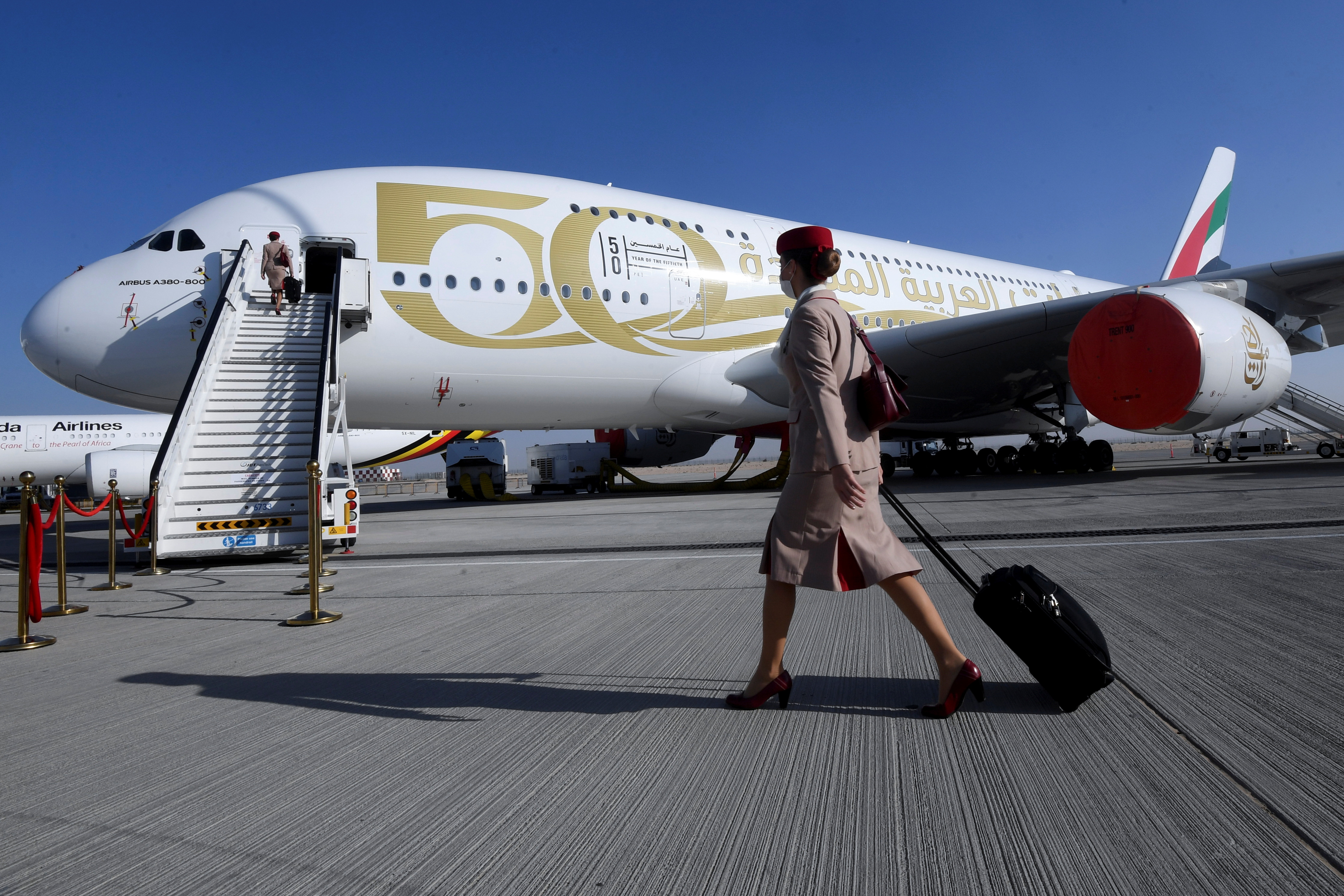 A crew member of the Emirates airline walks past an Emirates plane during the Dubai Air Show in Dubai, United Arab Emirates, November 15, 2021. REUTERS/Stringer