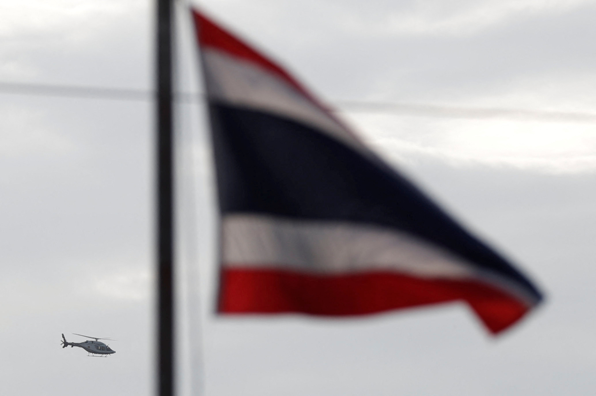 A helicopter carrying rescued schoolboys flies past a Thailand national flag in Chiang Rai