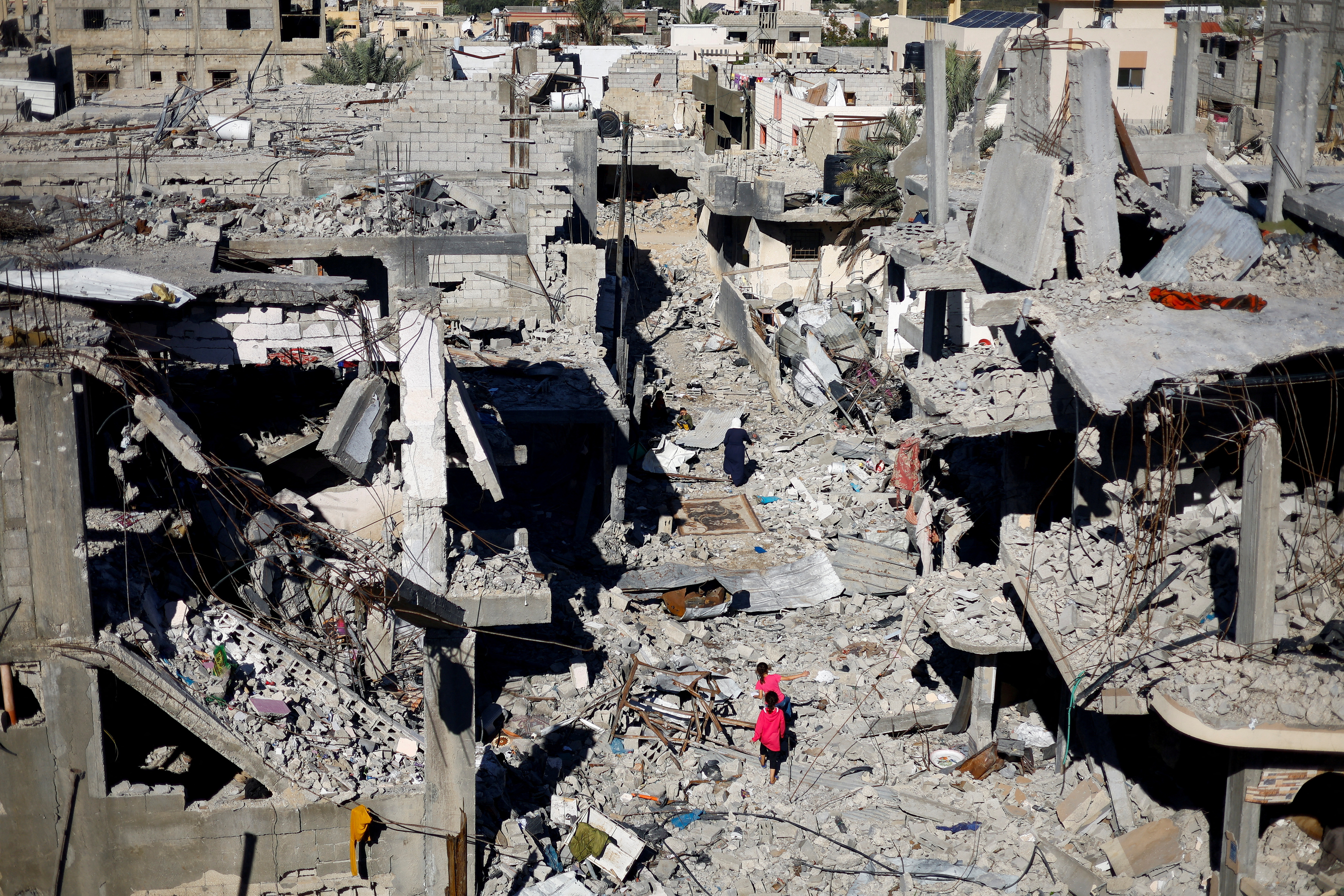 Palestinian children walk among the houses destroyed in Israeli strikes, at Khan Younis refugee camp