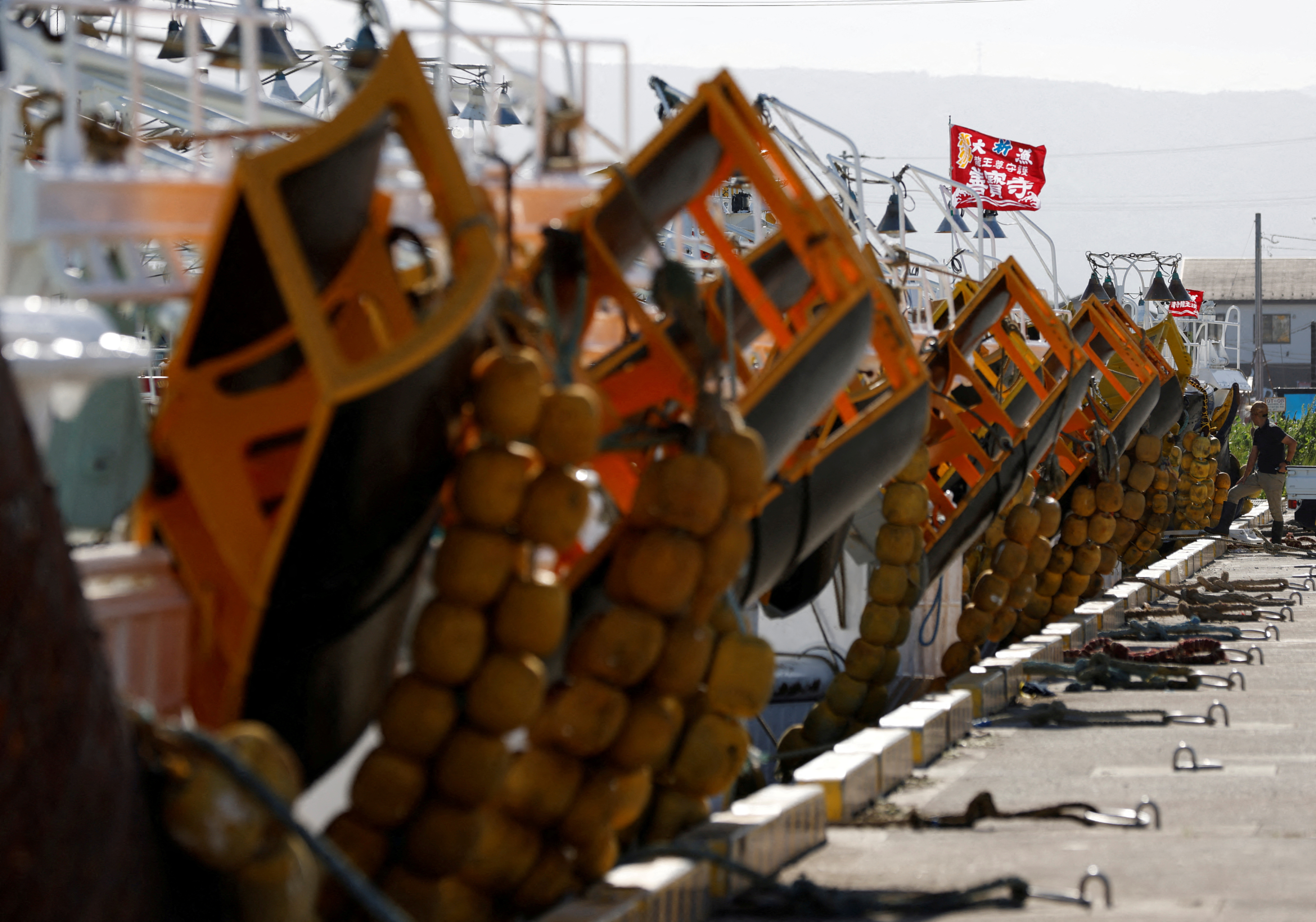 A fisherman stands next to fishing boats anchored at a fishing port in Soma