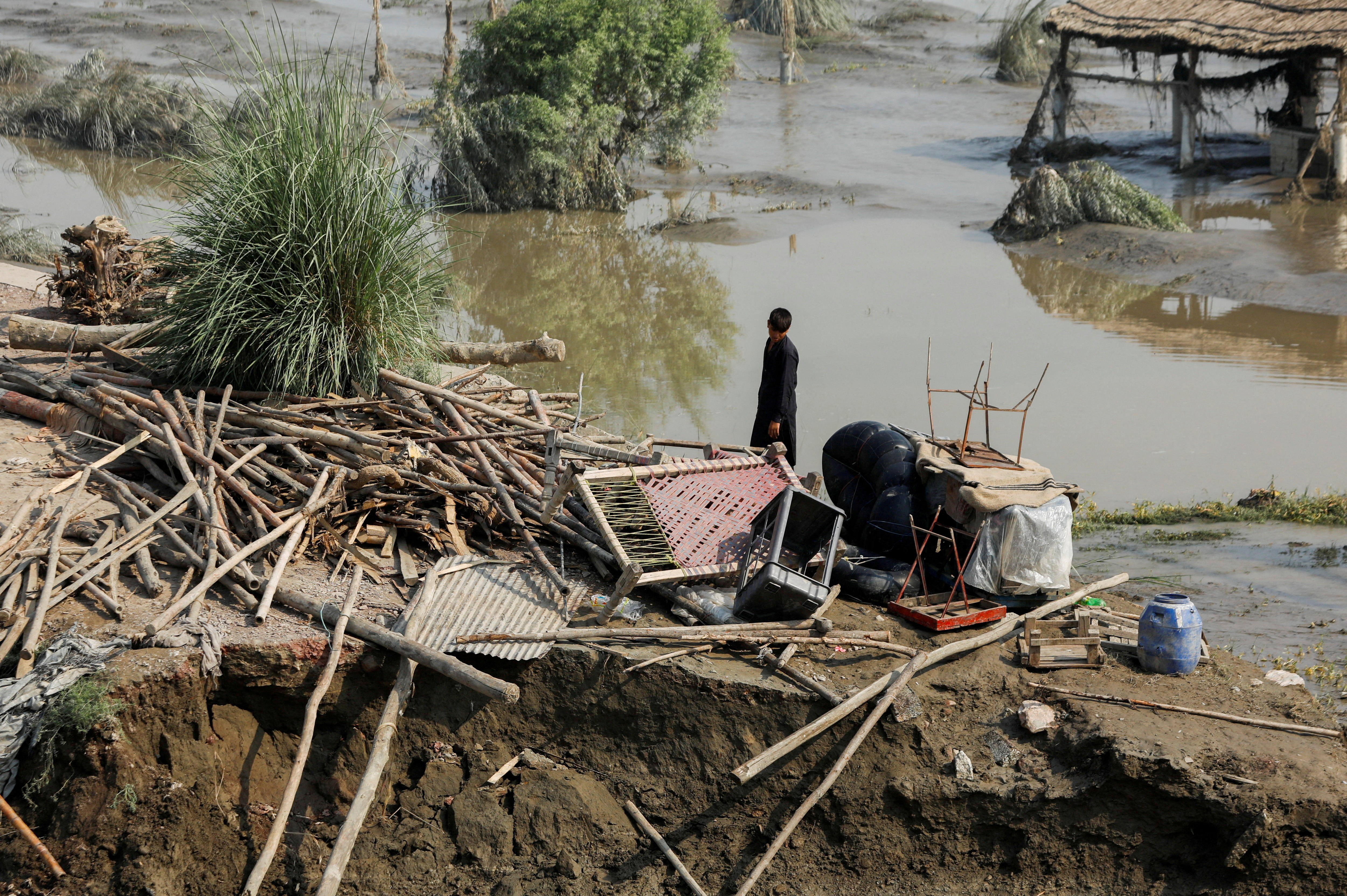 A flood victim stands in his damaged house following rains and floods during the monsoon season, in Nowshera