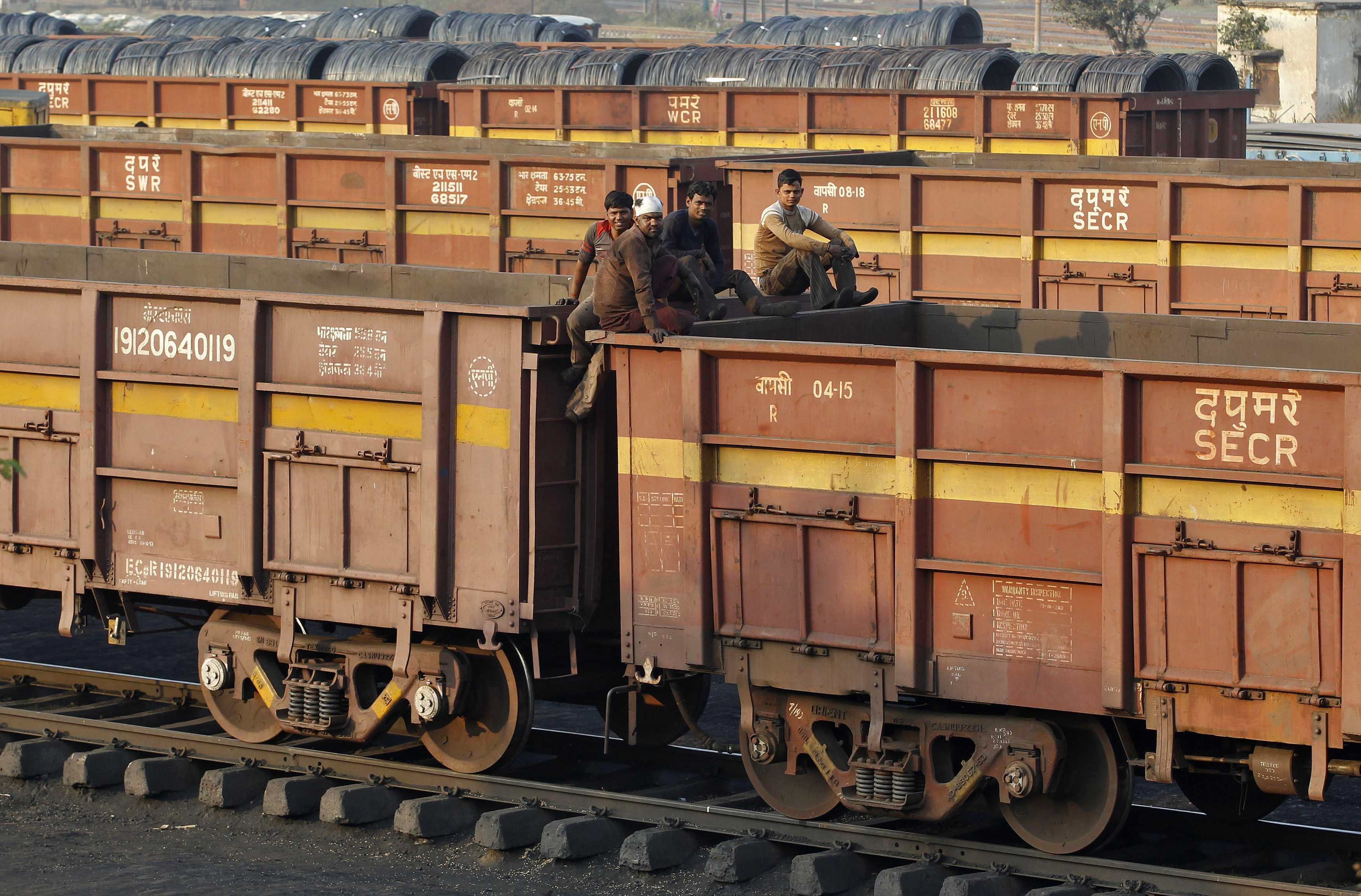 Workers sit on top of a goods train at a railway yard in Ahmedabad