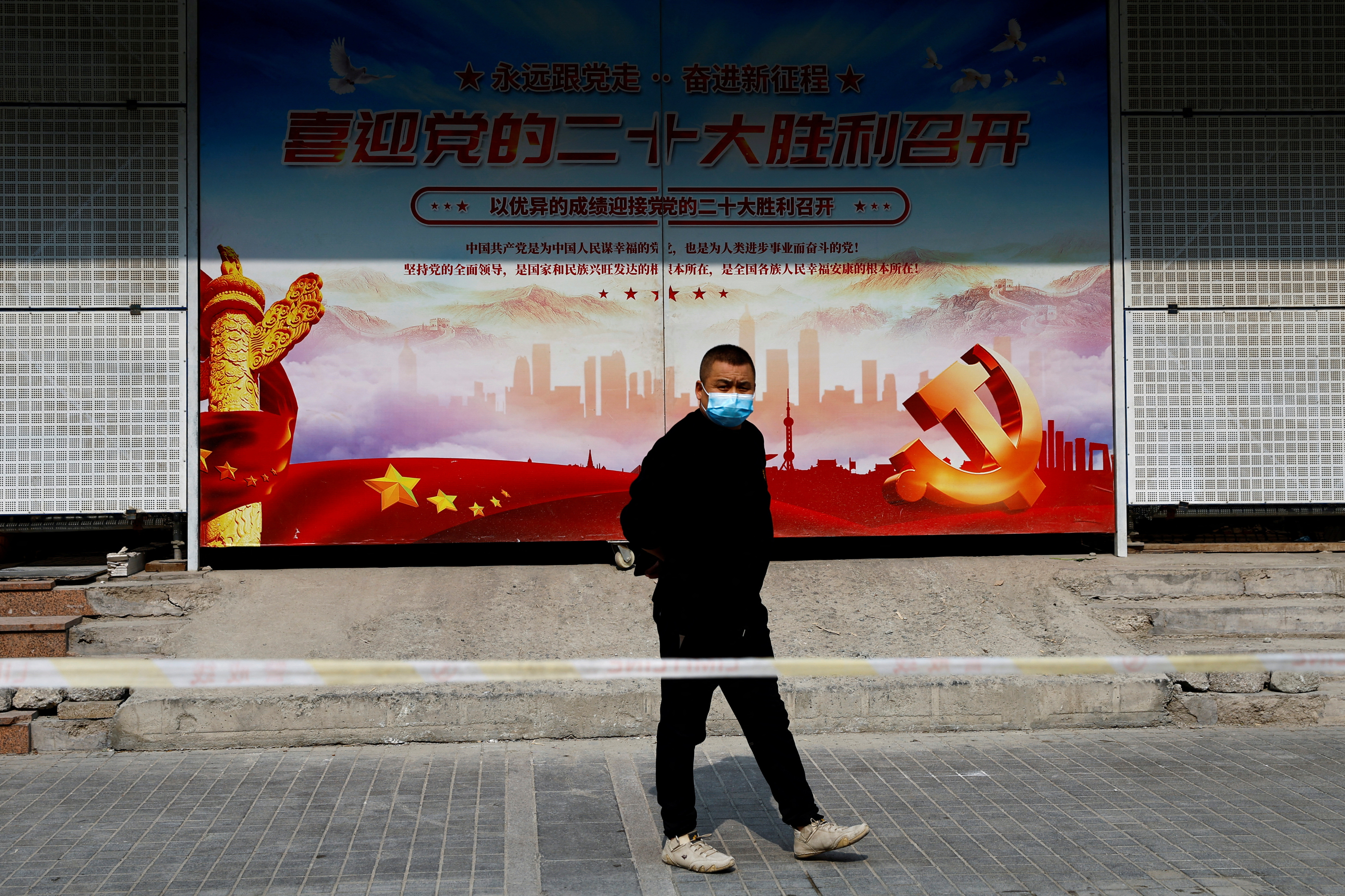 Man walks past a poster welcoming the 20th National Congress of the Communist Party of China, in Beijing