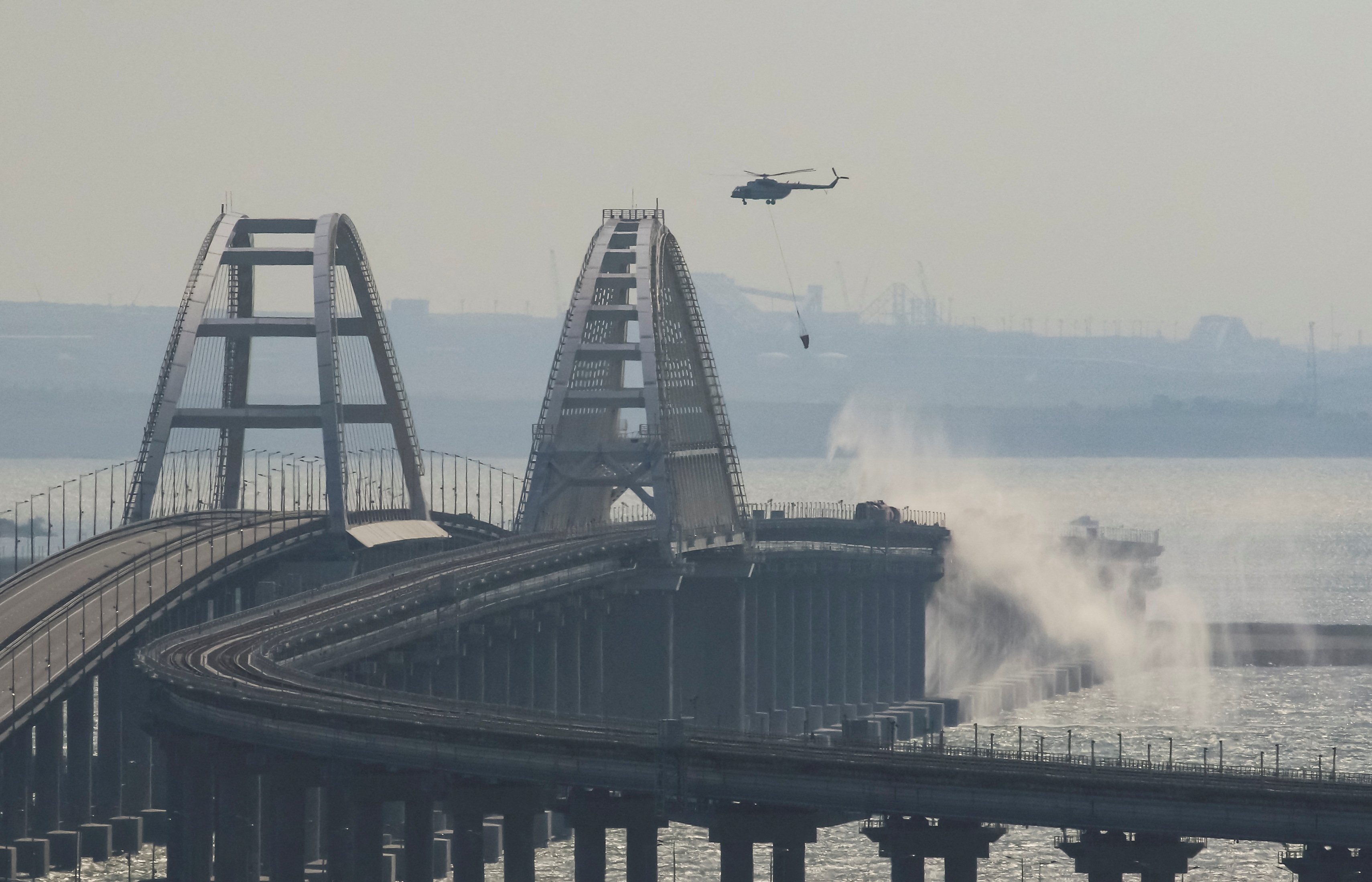 A helicopter drops water to extinguish fuel tanks ablaze on the Kerch bridge in the Kerch Strait, Crimea