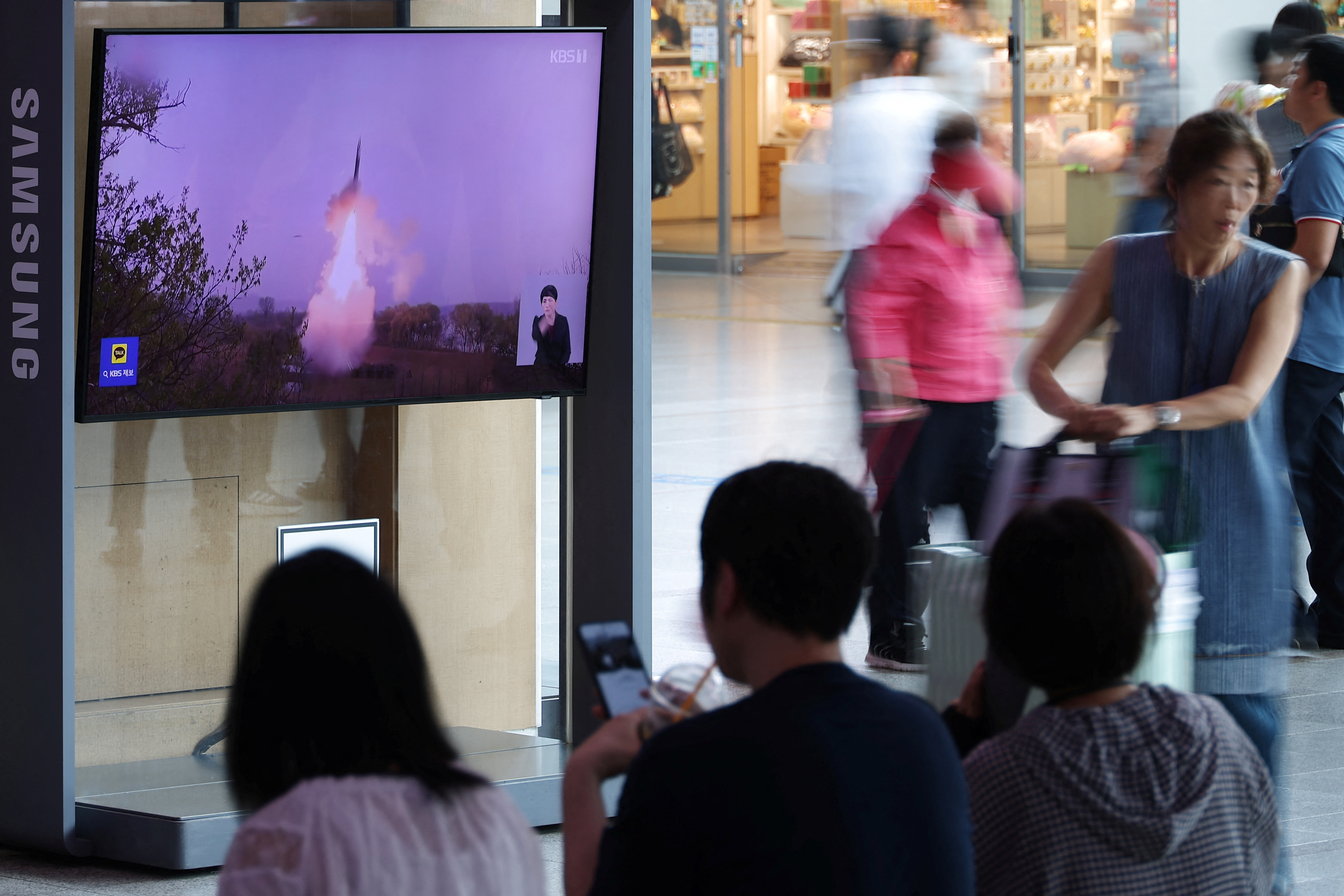 Passengers wait for their train in front of a TV broadcasting a news report on North Korea firing a ballistic missile off its east coast, at a railway station in Seoul