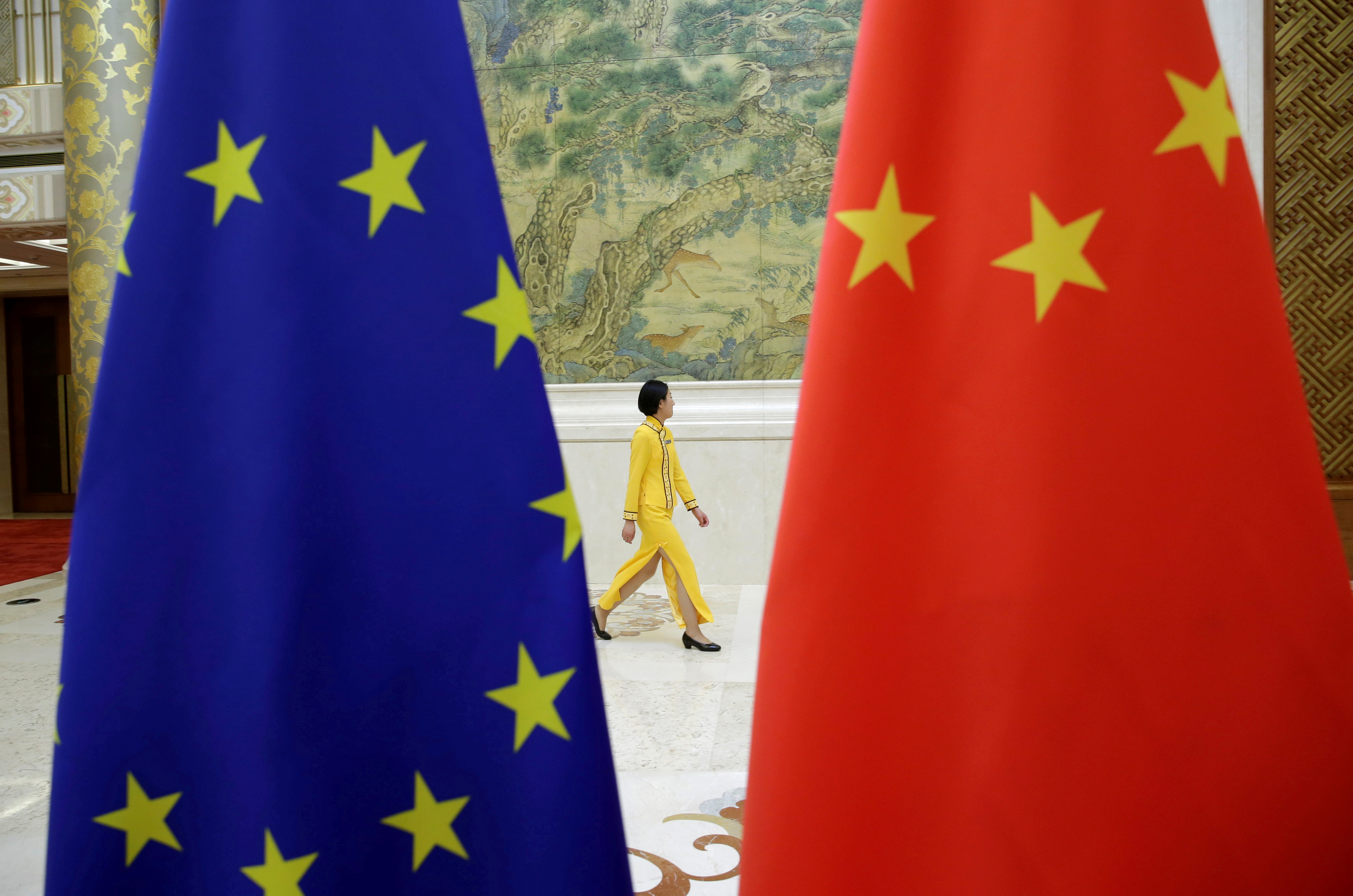 An attendant walks past EU and China flags ahead of the EU-China High-level Economic Dialogue in Beijing