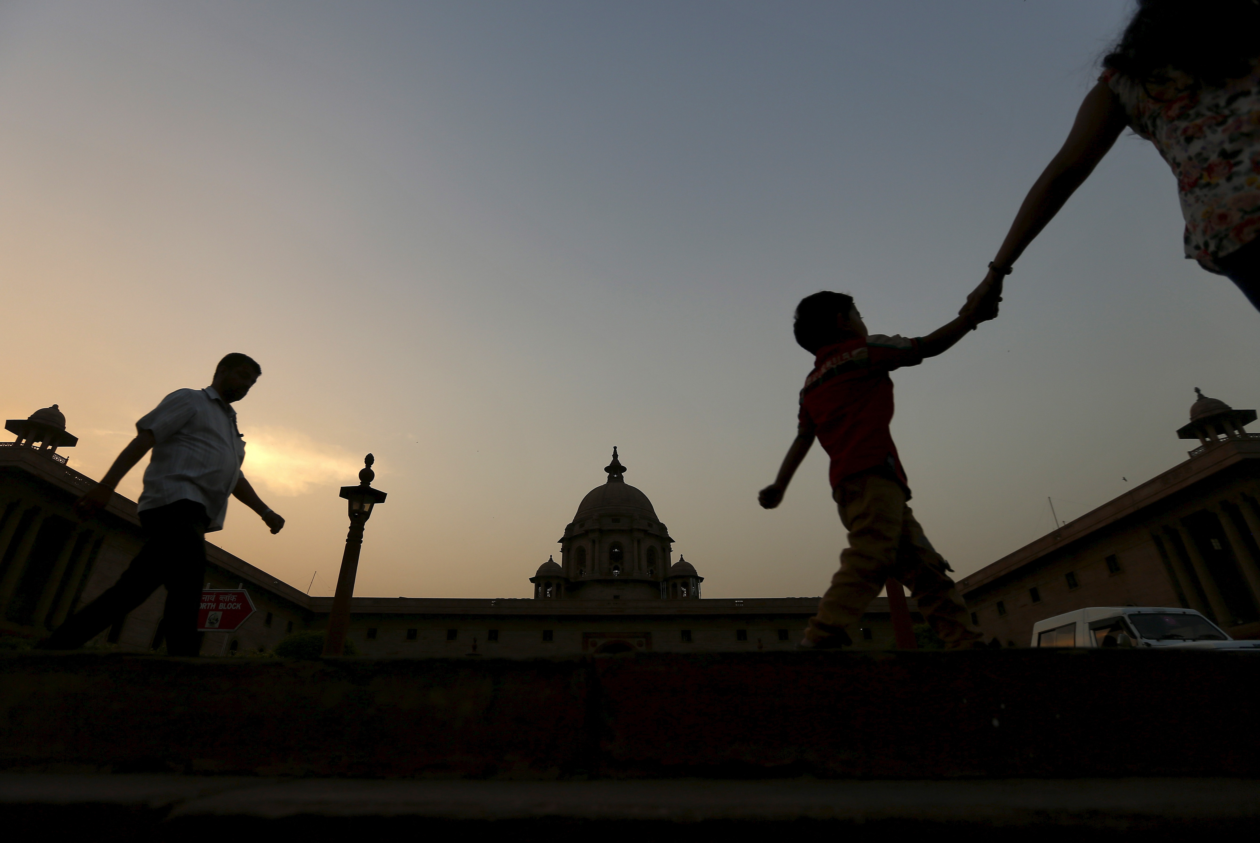 Commuters walk past the building of India's Ministry of Finance during dusk in New Delhi
