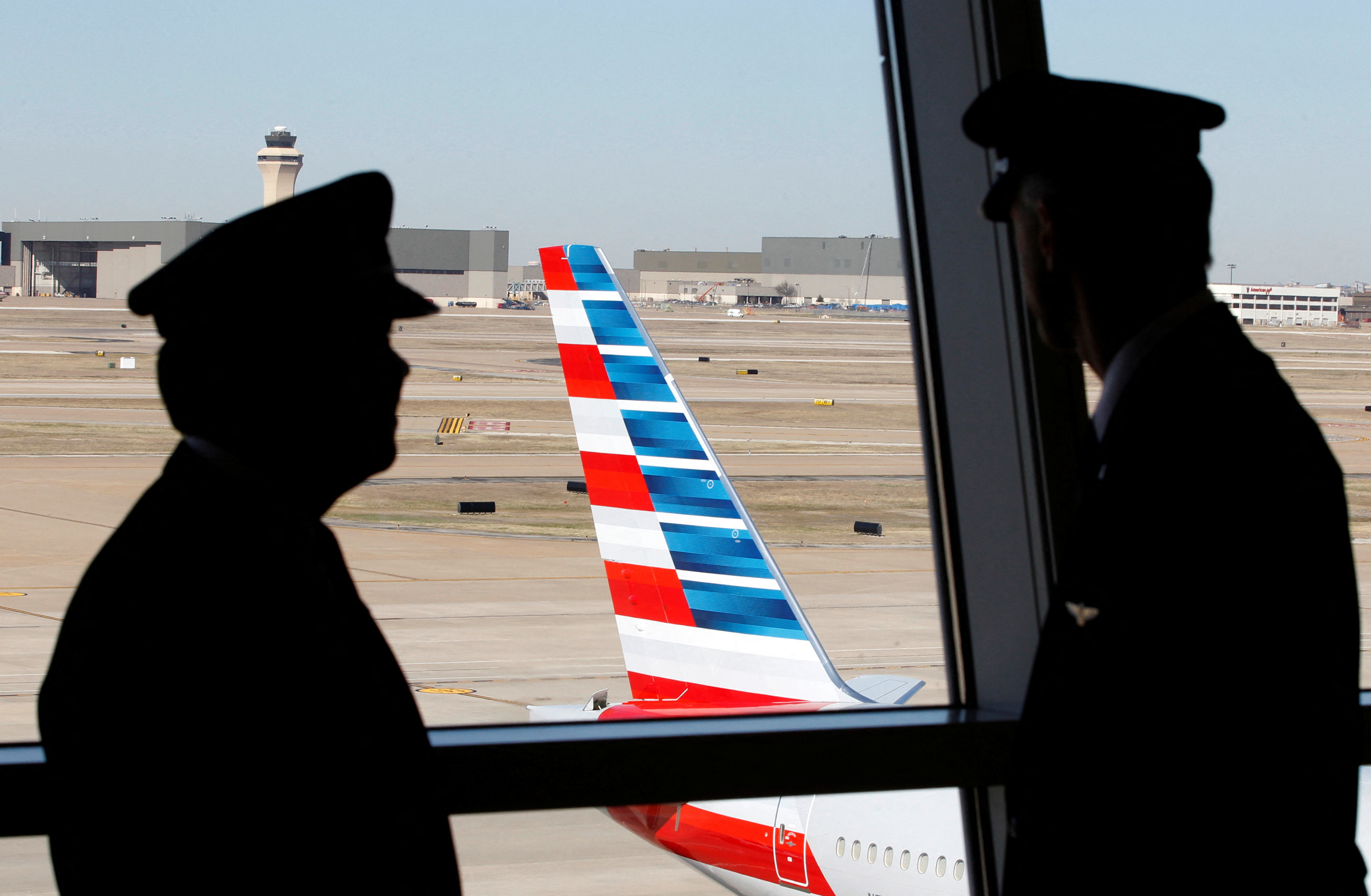 Pilots talk as they look at the tail of an American Airlines aircraft at Dallas-Ft Worth International Airport