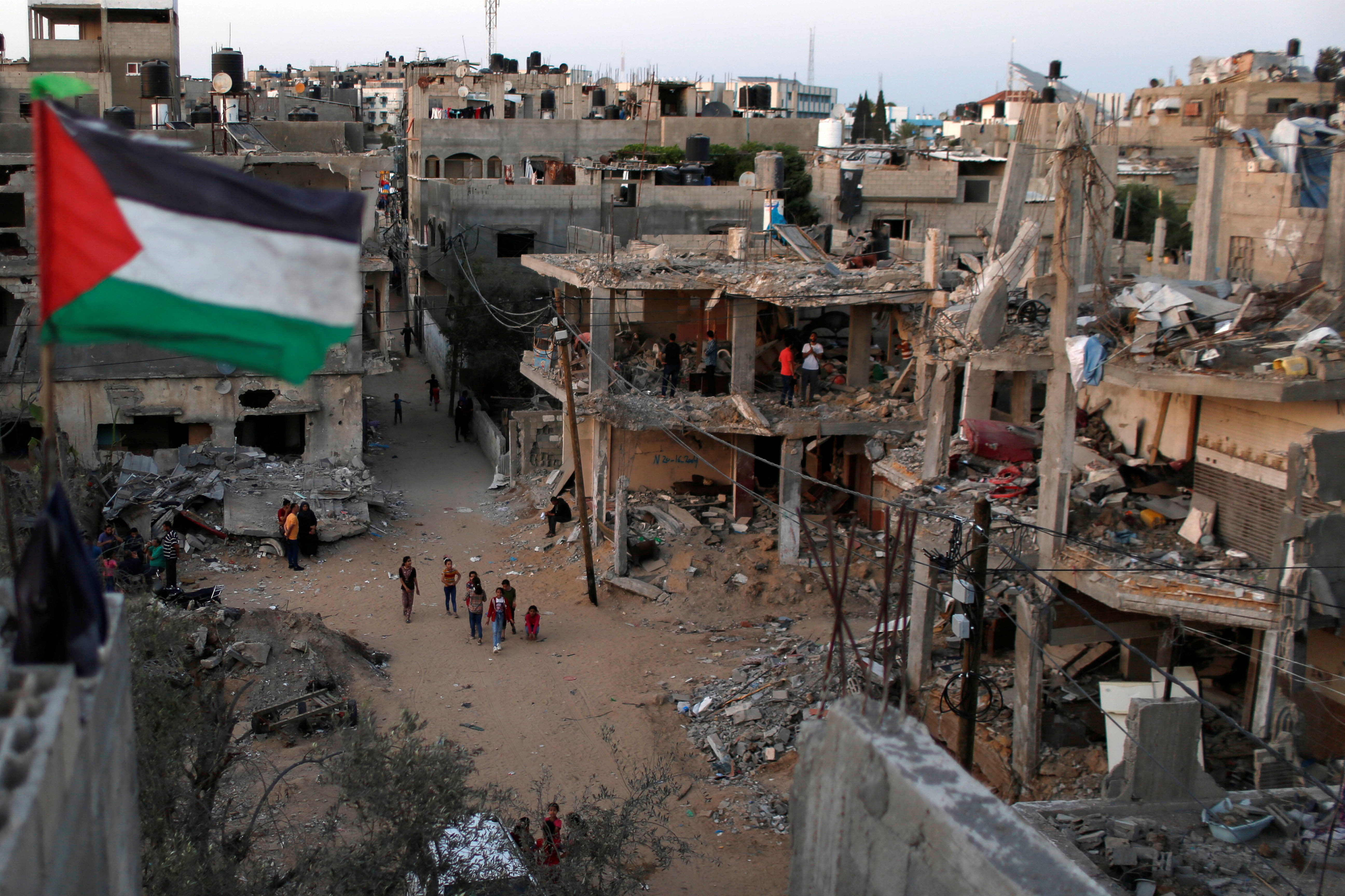 A Palestinian flag flies as the ruins of houses, which were destroyed by Israeli air strikes during the Israeli-Palestinian fighting, are seen, in Gaza