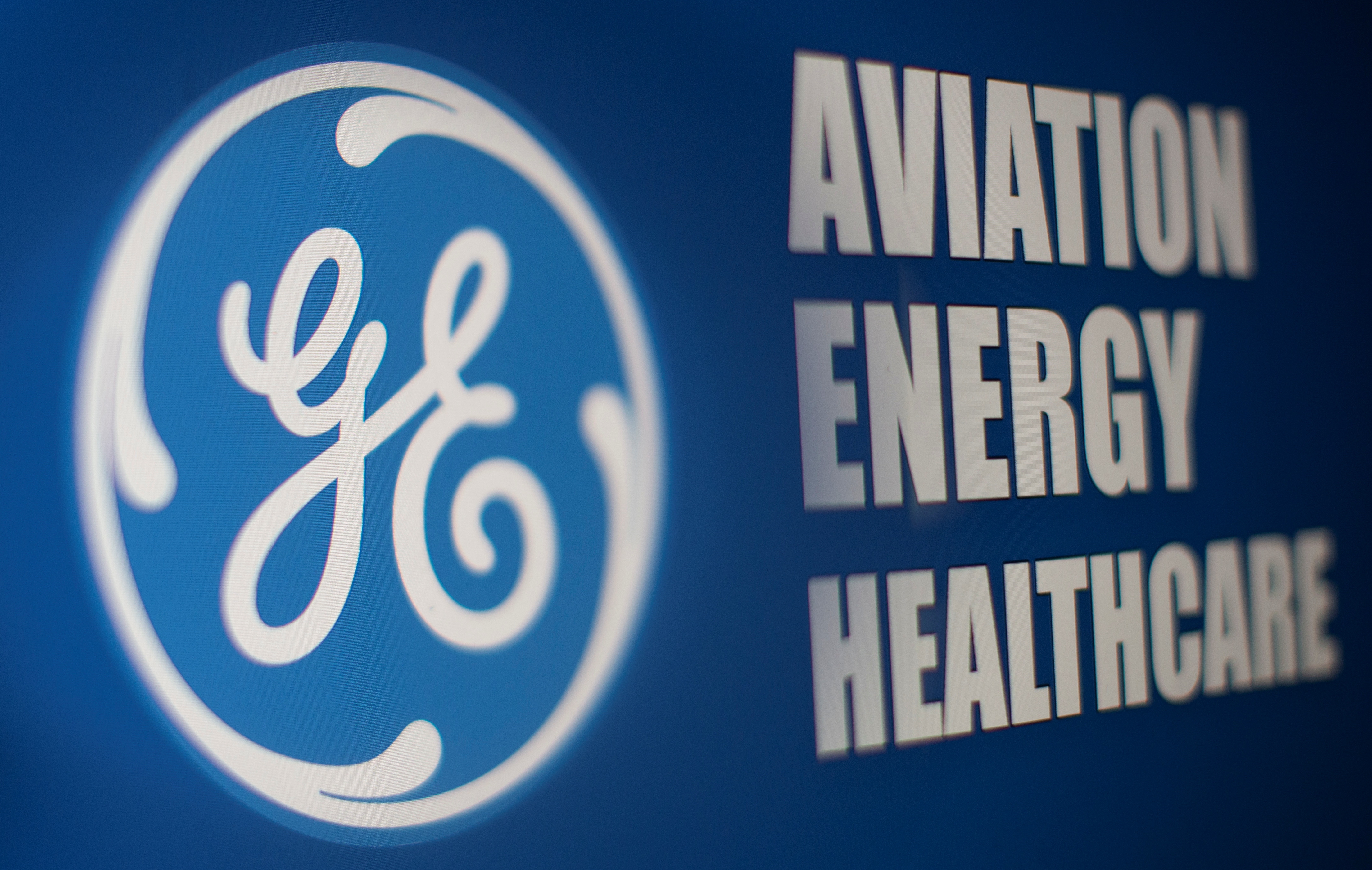 General Electric logo is seen through magnifier in front of displayed Aviation, Energy, Healthcare words in this illustration taken