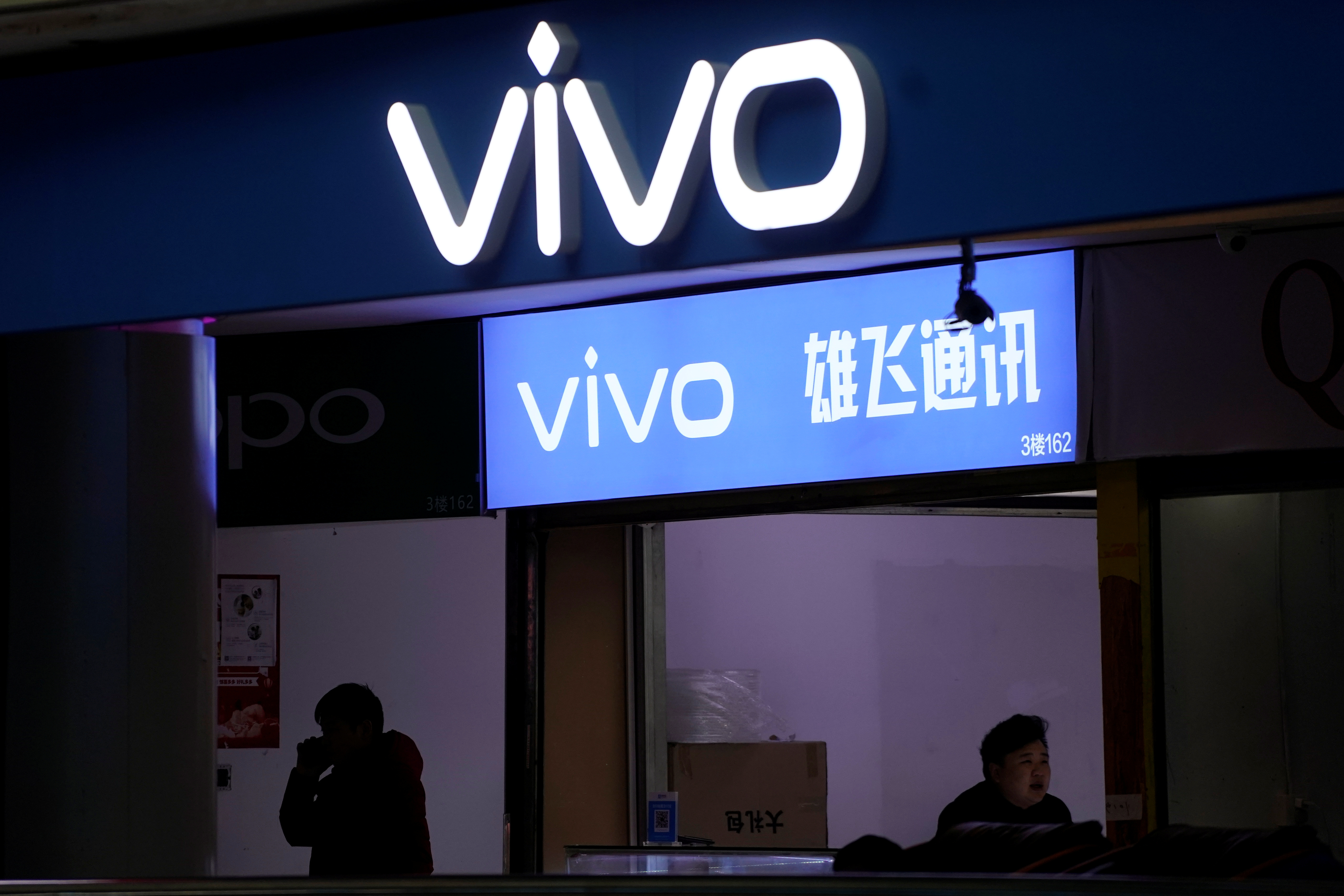 A man walks by a VIVO logo at a shopping mall in Shanghai