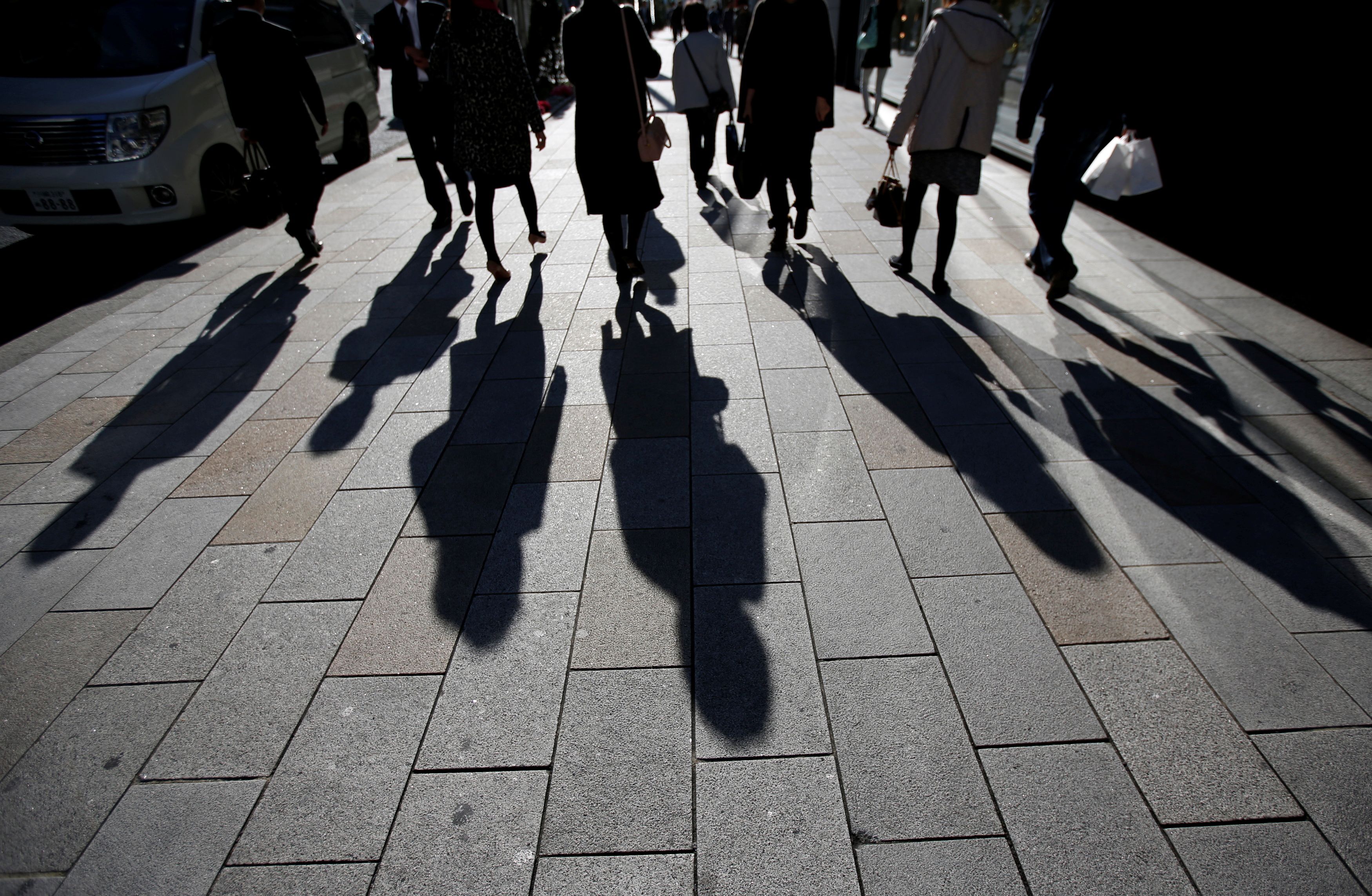 Shadows of pedestrians are pictured cast on a street in Tokyo
