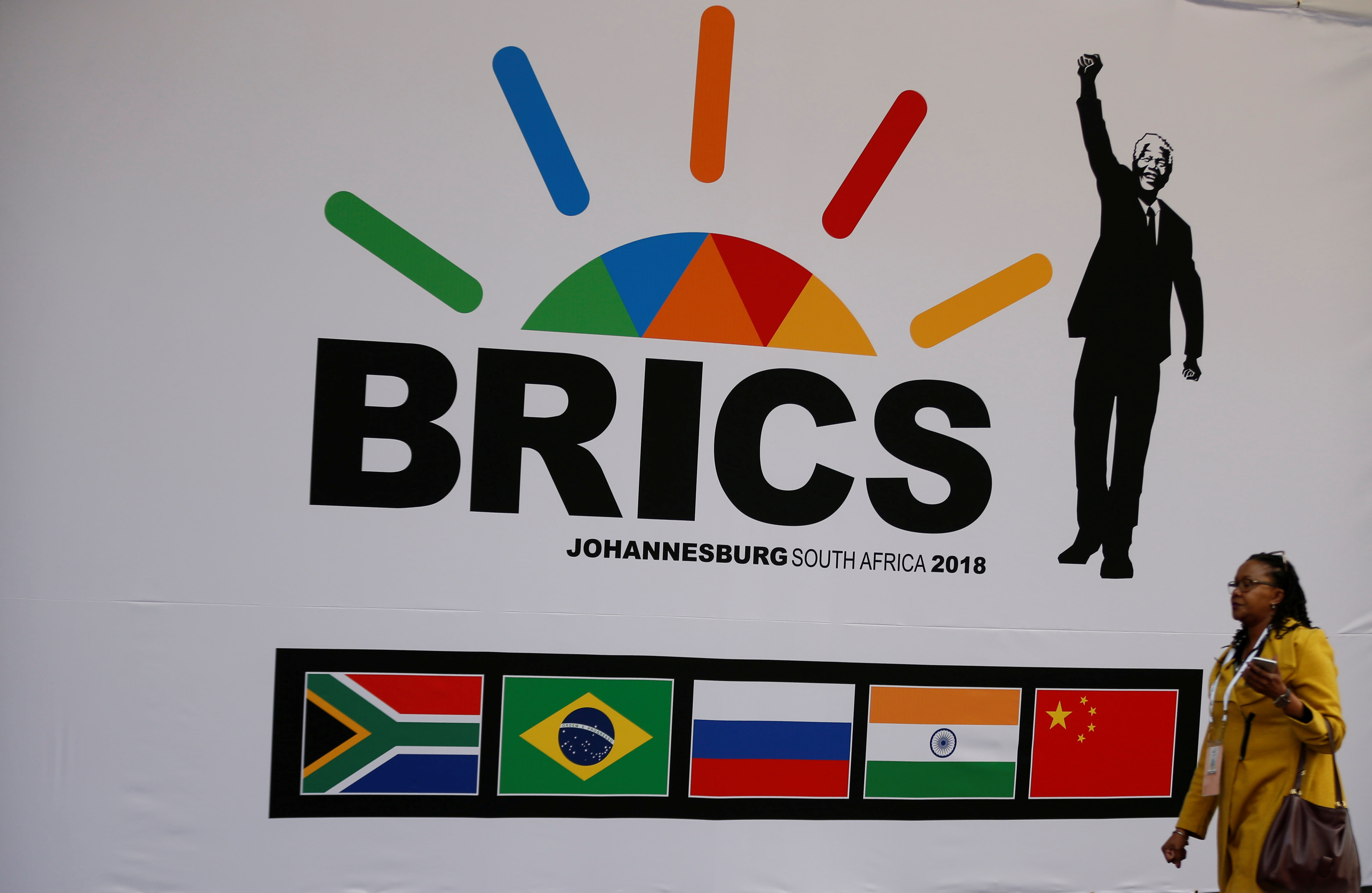 A delegate walks past a BRICS logo ahead of the 10th BRICS Summit, in Sandton