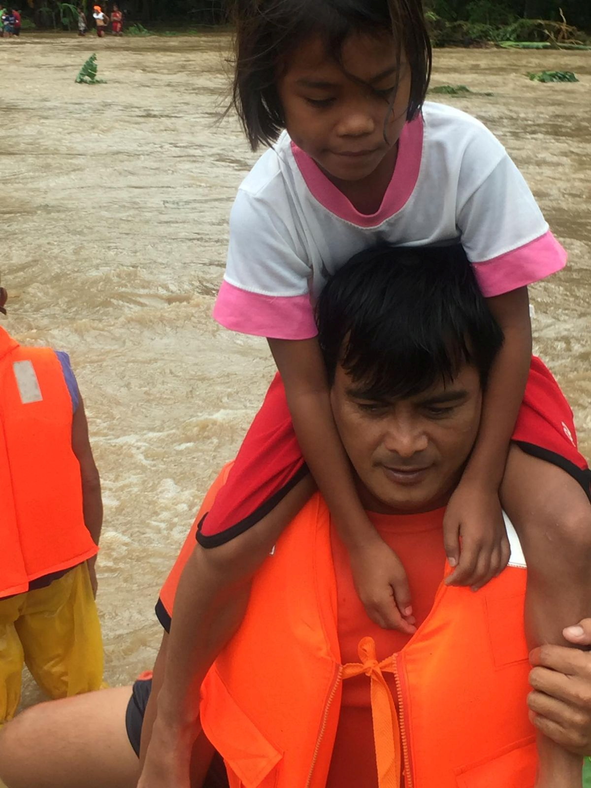 People cross floodwaters caused by tropical cyclone Kompasu during an evacuation assisted by the Philippine Coast Guard (PCG) at Brooke's Point, Palawan, in the Philippines