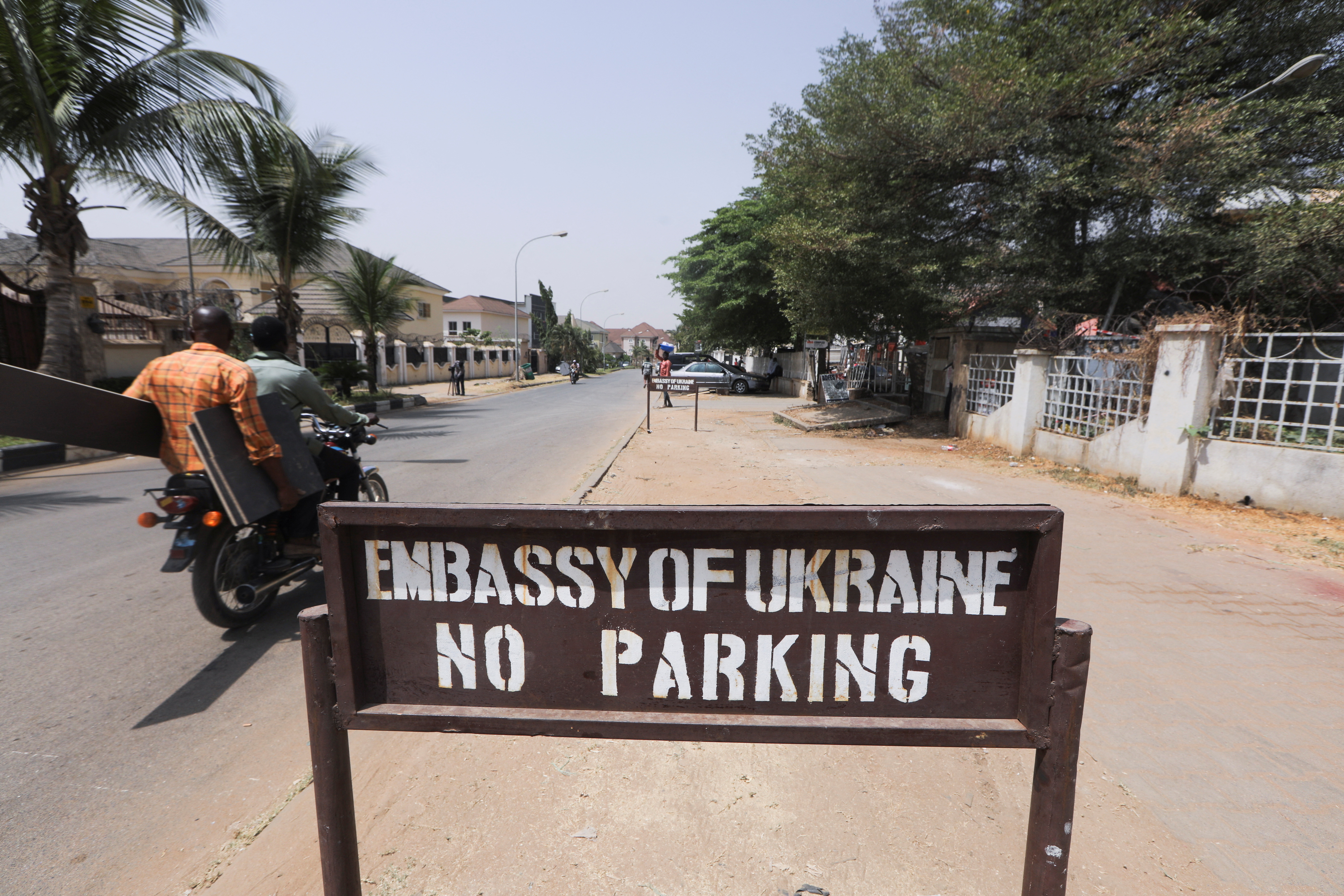 People on a motorbike drive past the Ukrainian embassy in Abuja