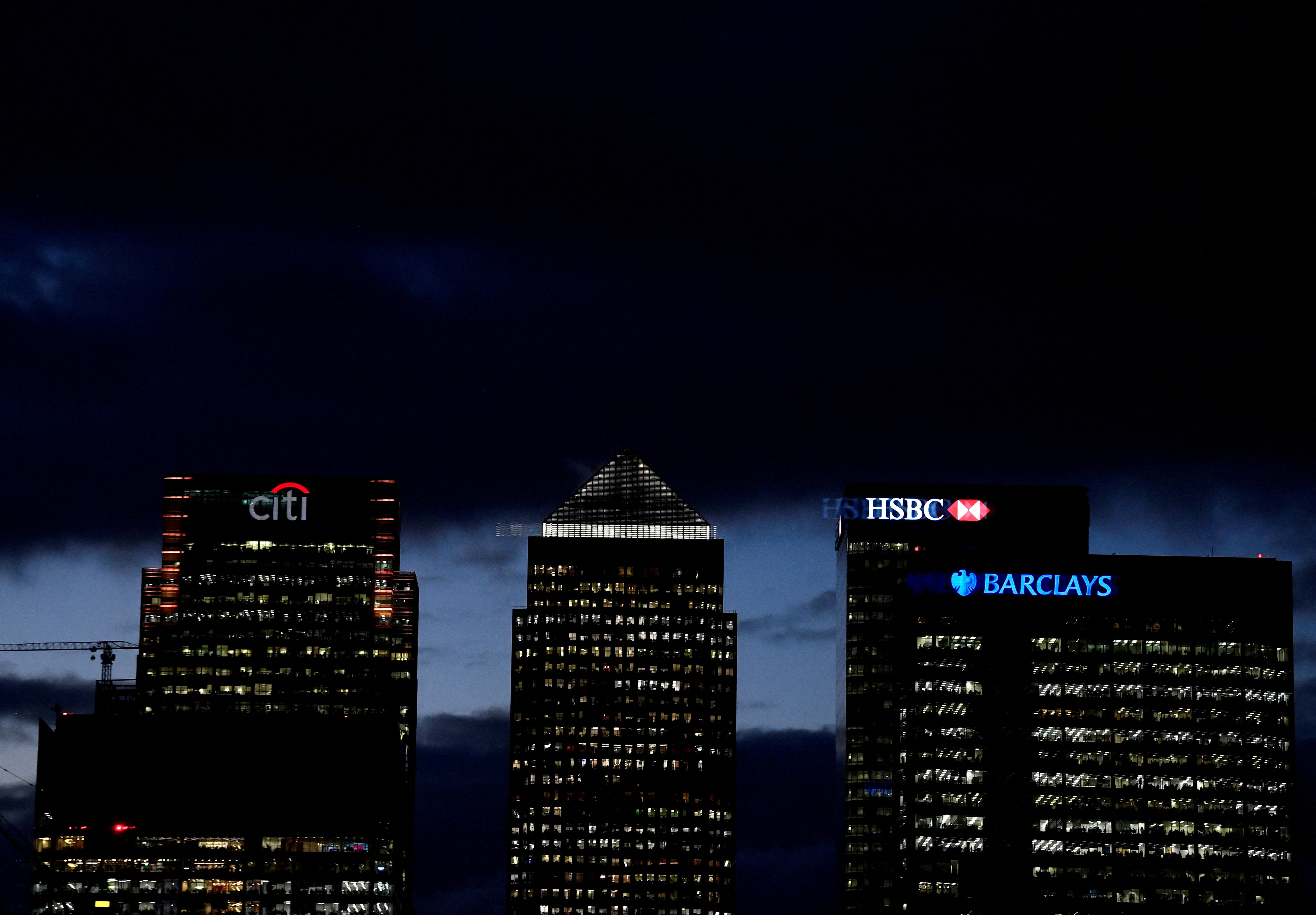 Citibank, HSBC and Barclay's buildings are lit up at dusk in the Canary Wharf financial district of London