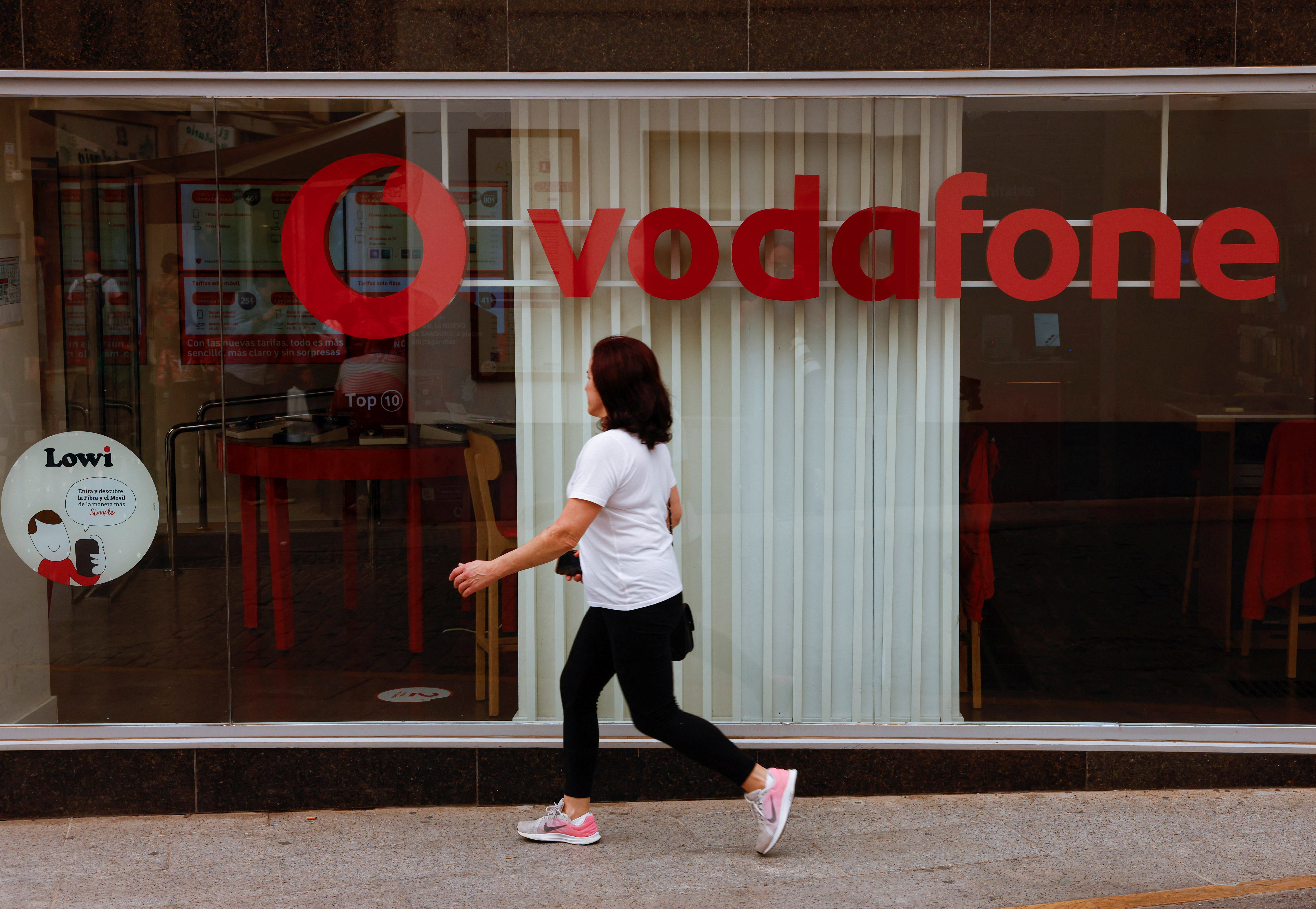 A woman walks past a Vodafone store in Ronda