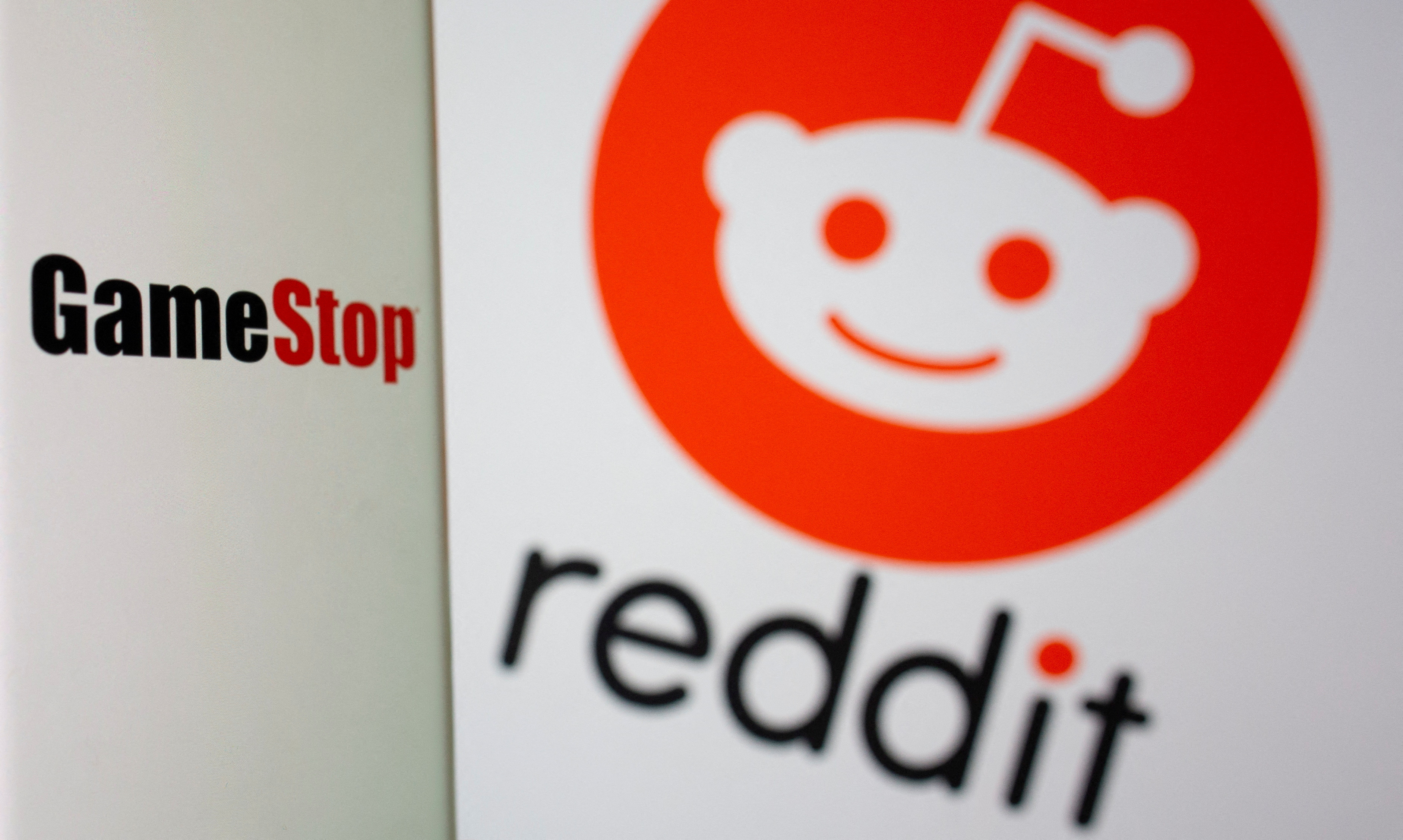 GameStop logo is seen in front of displayed Reddit logo in this illustration