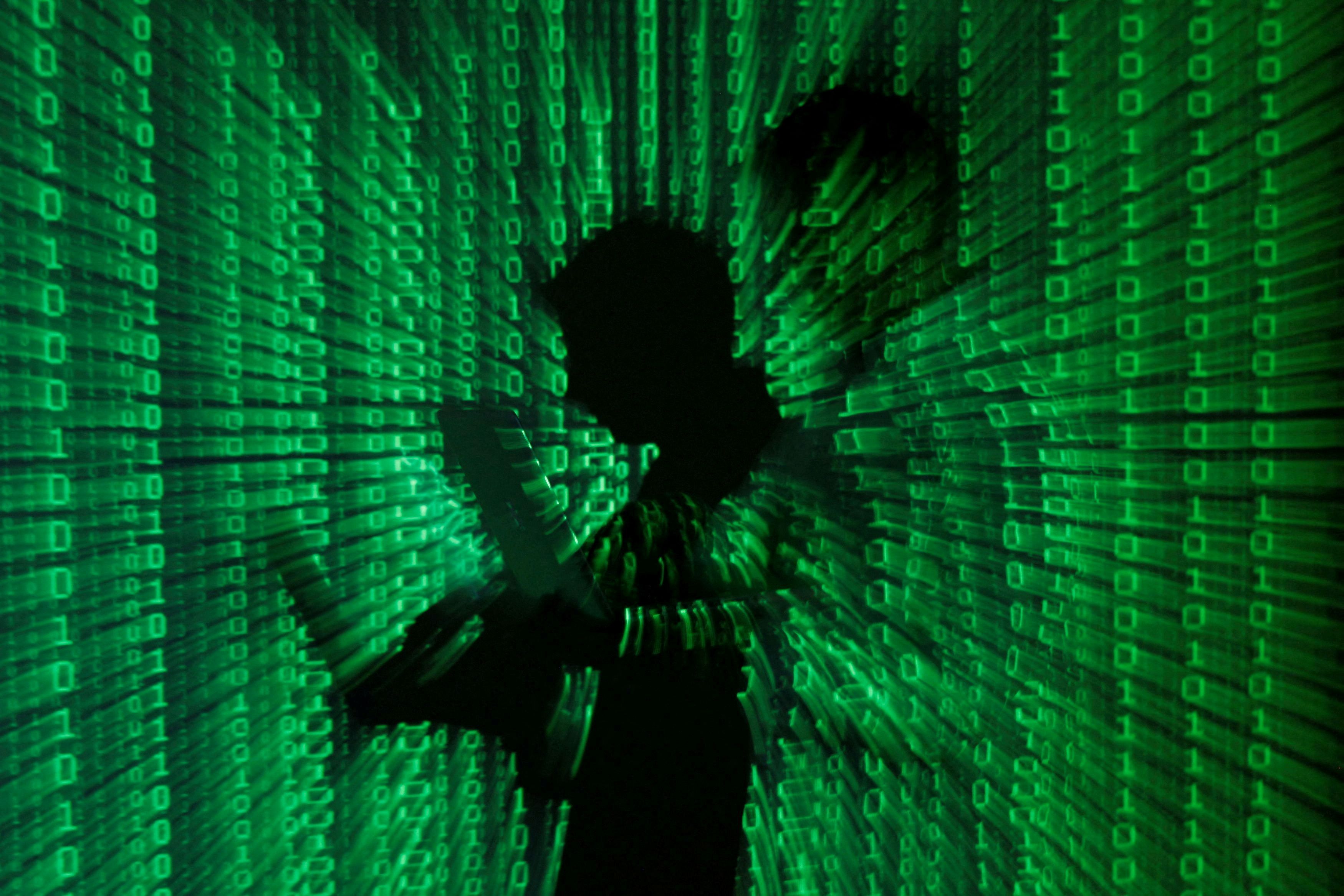 An illustration picture shows projection of binary code on man holding laptop computer