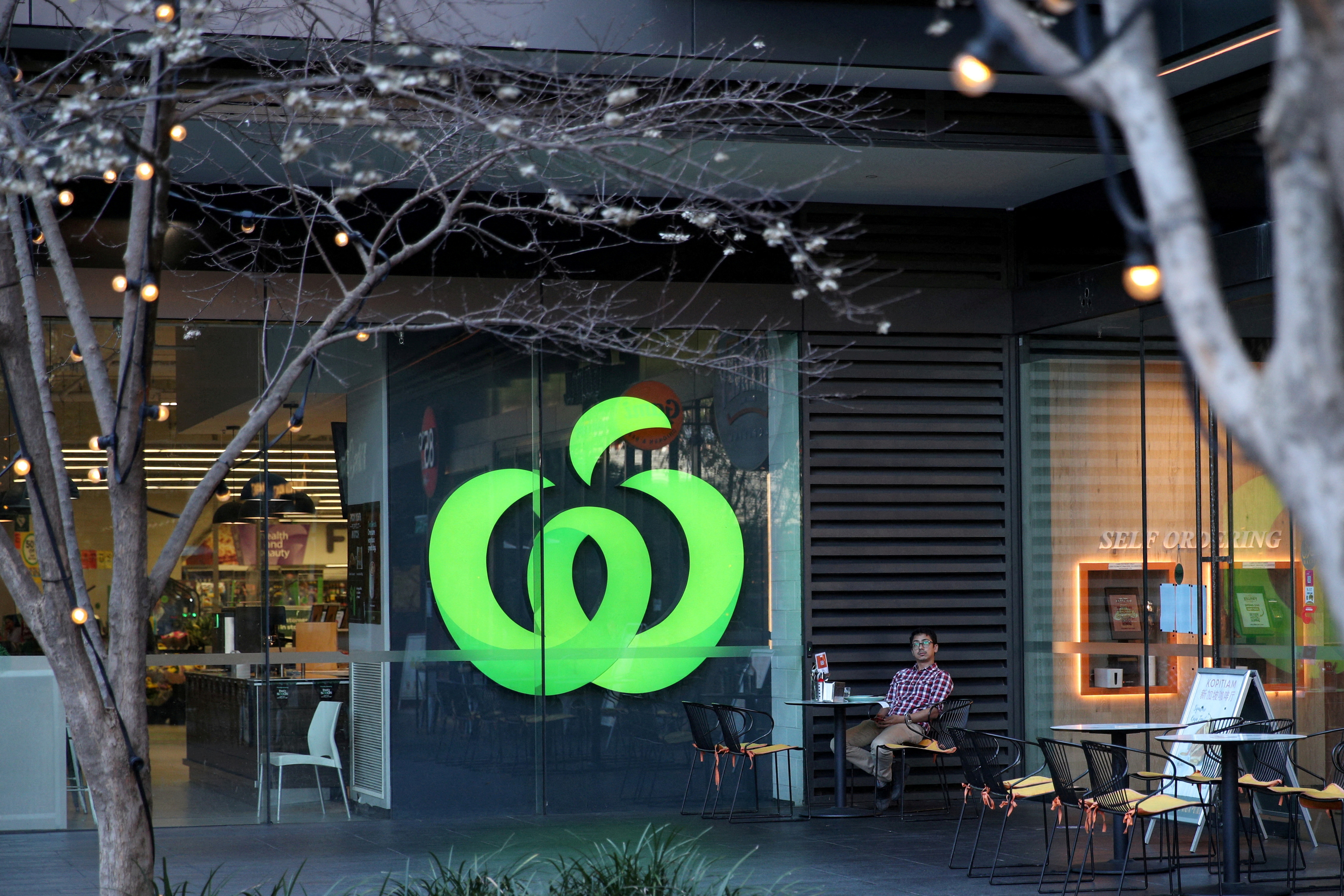 FILE PHOTO: A man sits outside a Woolworths supermarket in Sydney