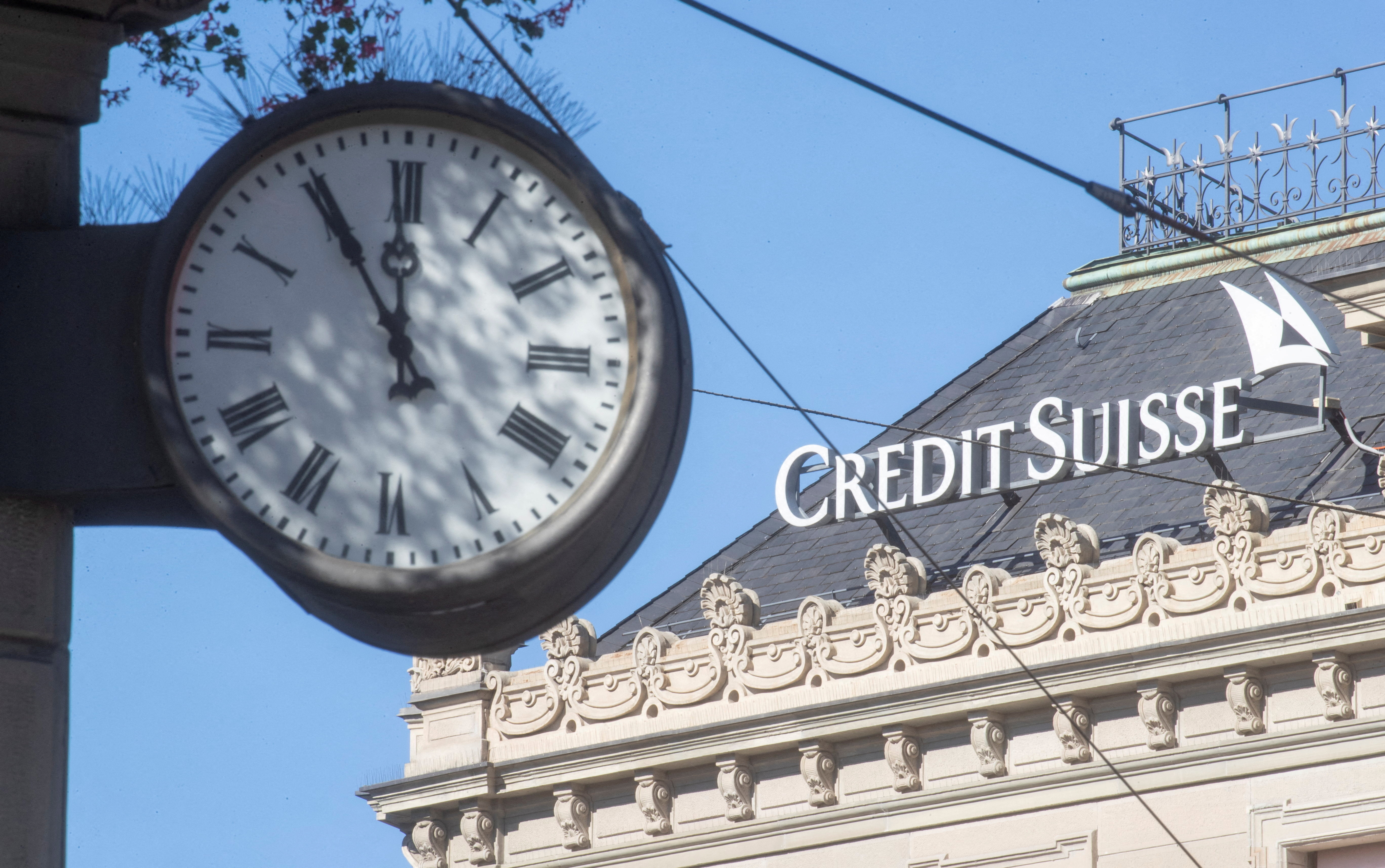 A clock is seen near the logo of the Swiss bank Credit Suisse in Zurich.
