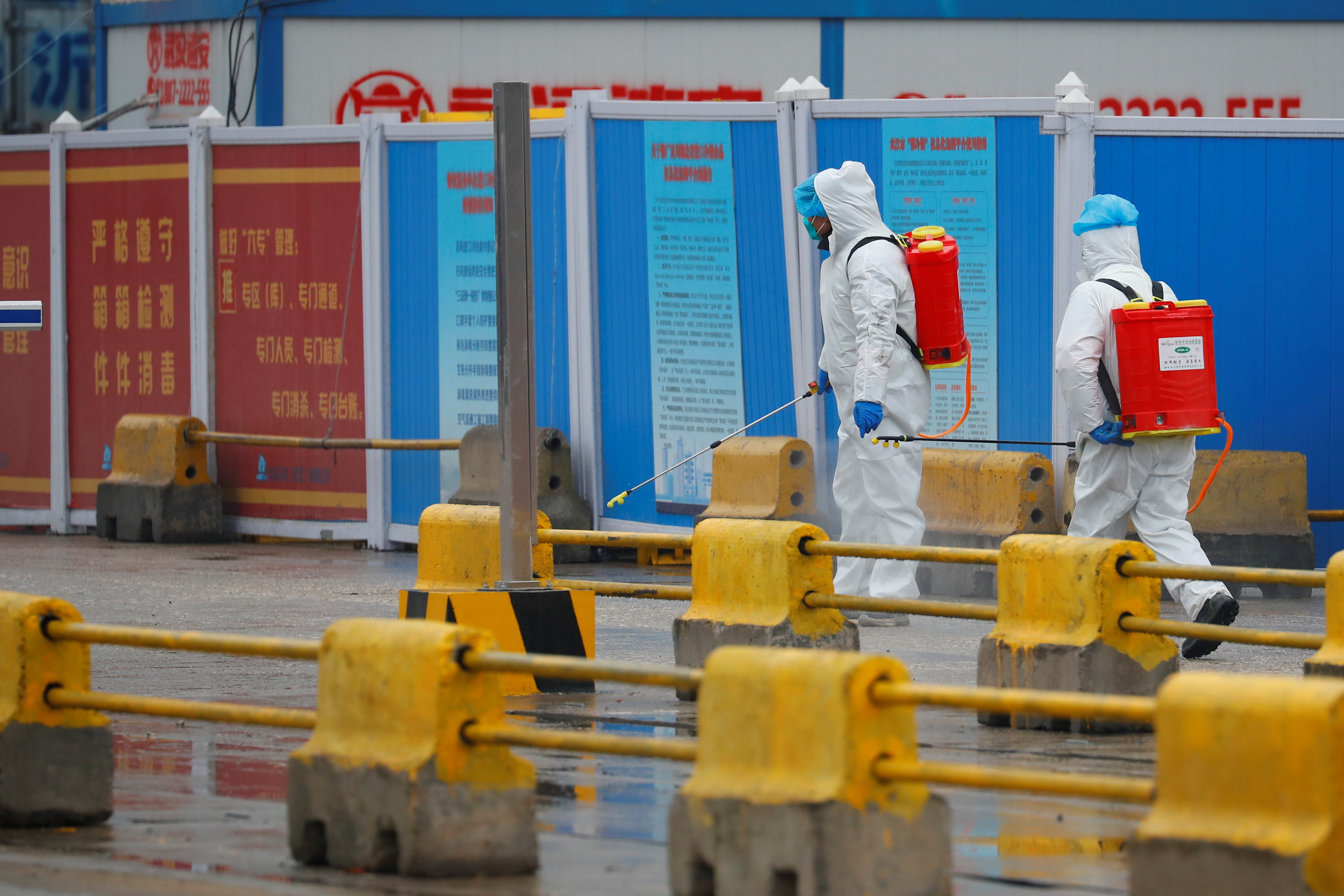 Workers in PPE spray the ground with diinfectant in Baishazhou market during a visit of World Health Organization (WHO) team tasked with investigating the origins of the coronavirus (COVID-19) pandemic, in Wuhan, Hubei province, China, January 31, 2021. REUTERS/Thomas Peter