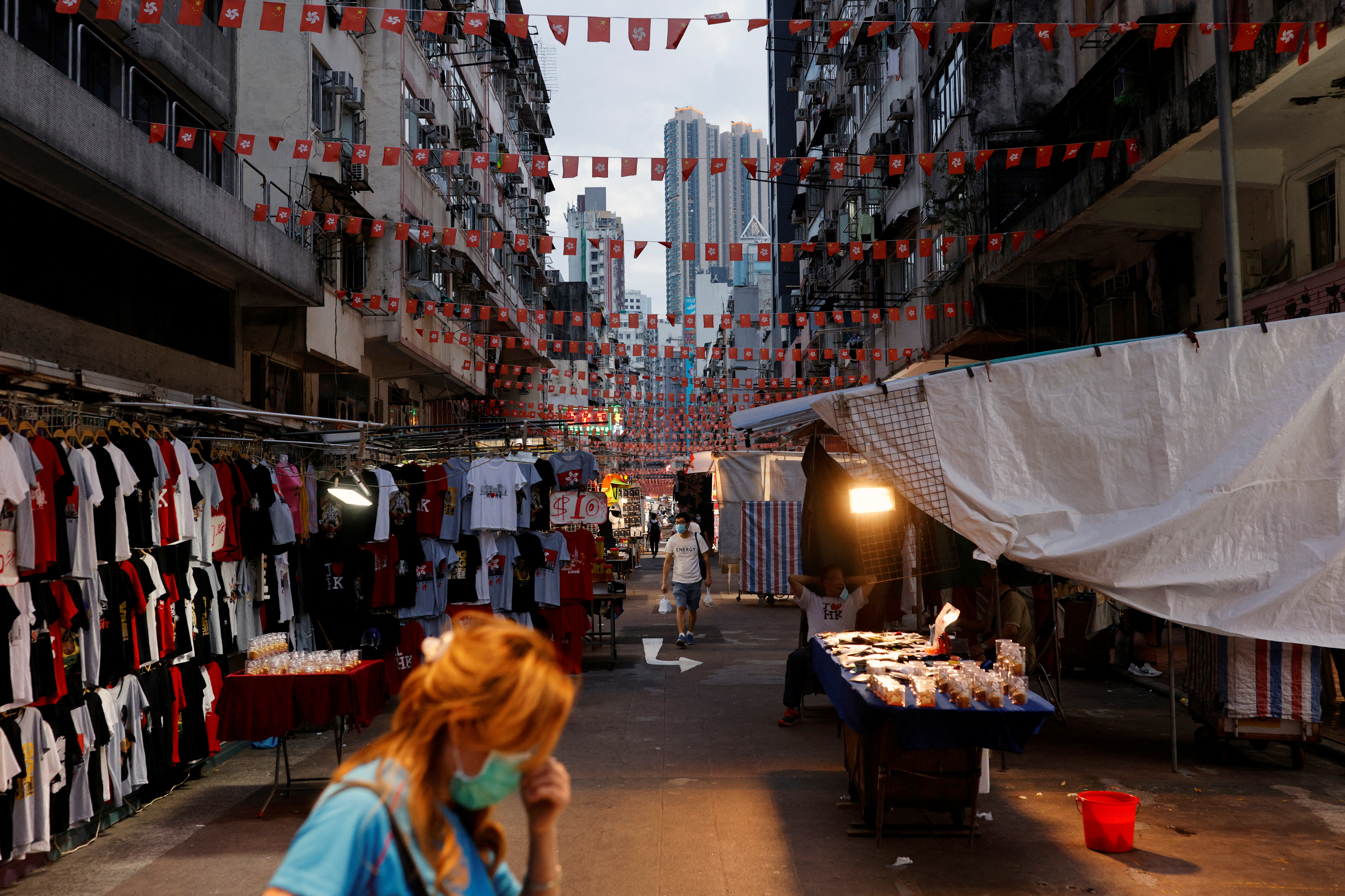People walk underneath rows of Chinese and Hong Kong flags hanging over Temple Street in Hong Kong