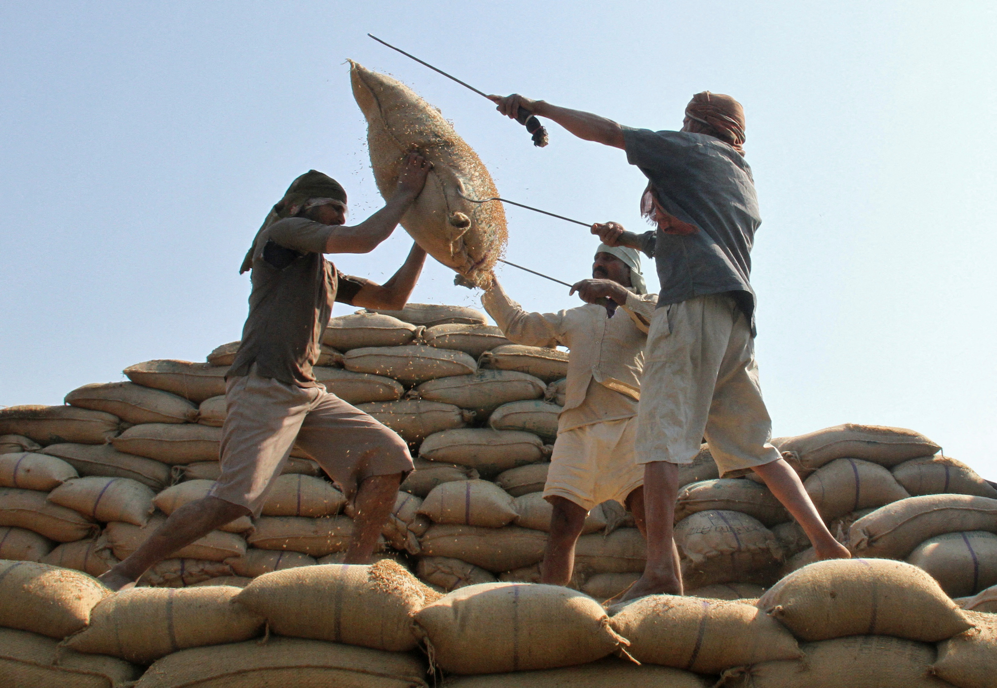 Workers lift a sack of rice to load onto a truck at a wholesale grain market in Chandigarh, India